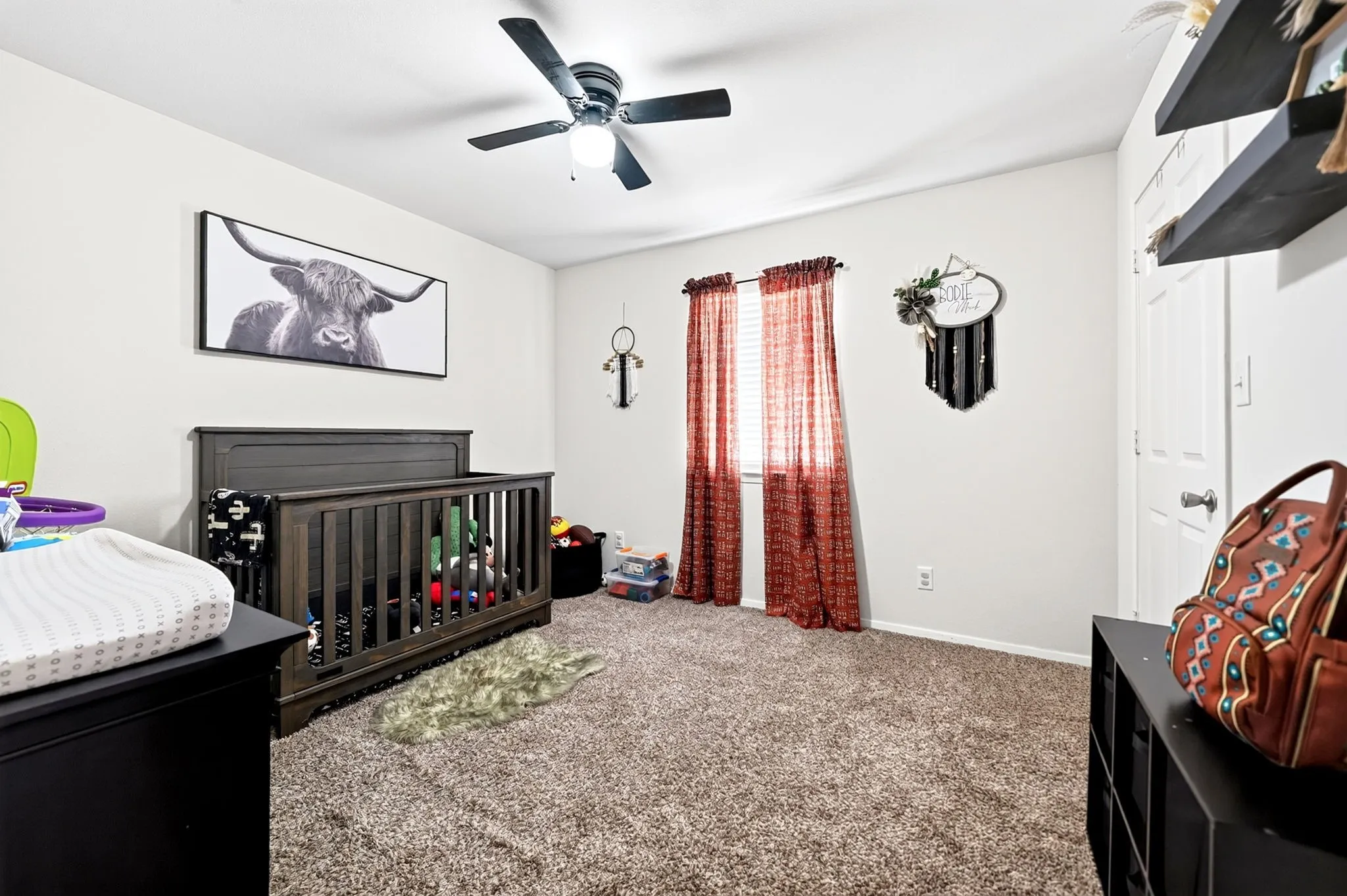 Spacious room featuring neutral wall paint, carpet flooring, a ceiling fan with integrated lighting, and a single window with blinds