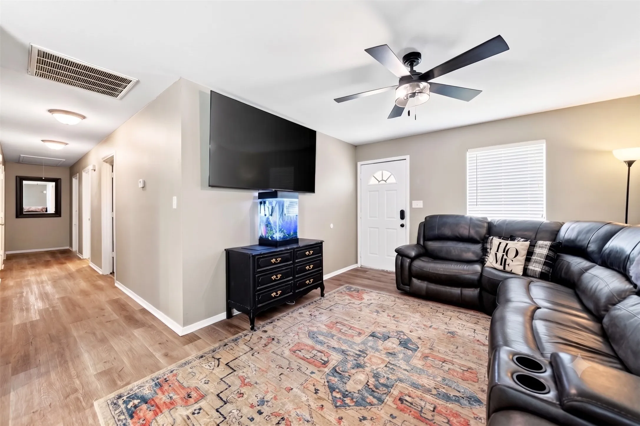 Open living area with wood-finish flooring, neutral wall tones, and a modern ceiling fan with light fixture