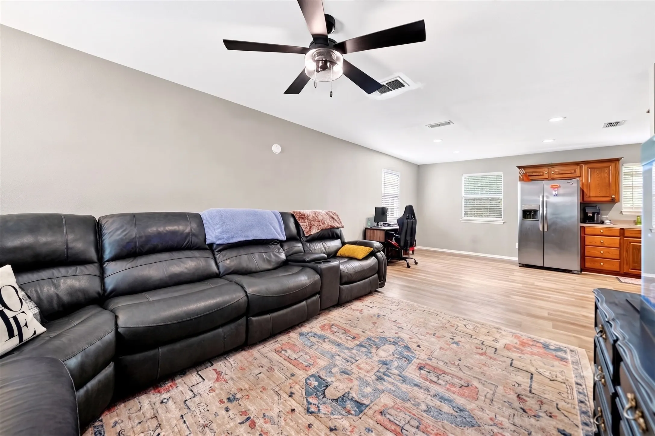 Open-concept living space with wood-finish flooring, a contemporary ceiling fan, recessed lighting, and neutral wall tones