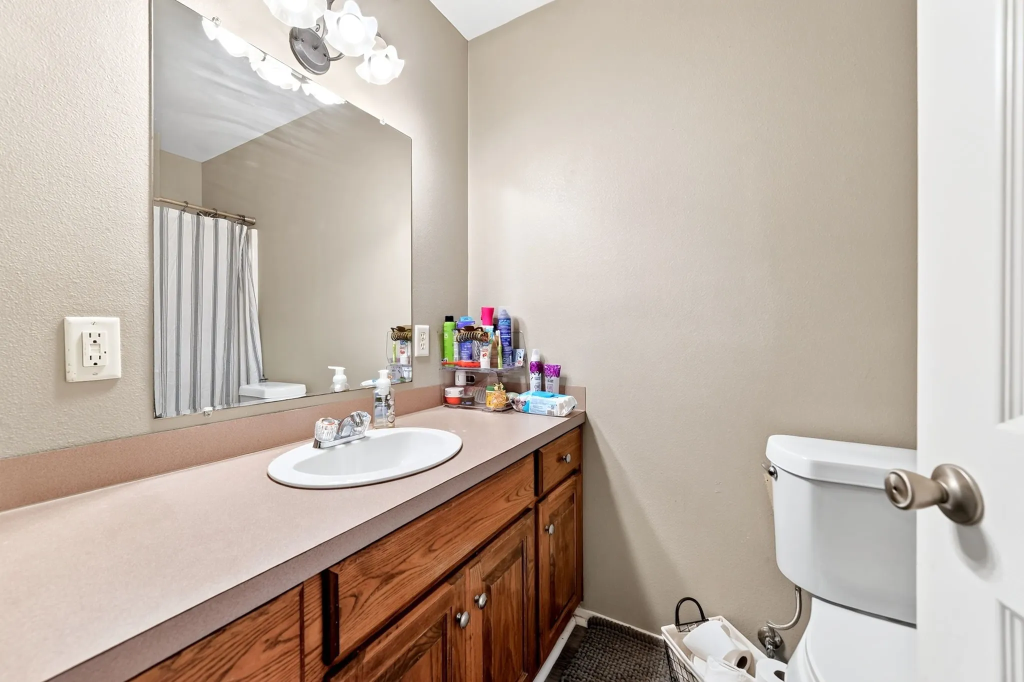 Spacious vanity featuring an integrated sink, wood-finish cabinetry, and an expansive wall mirror