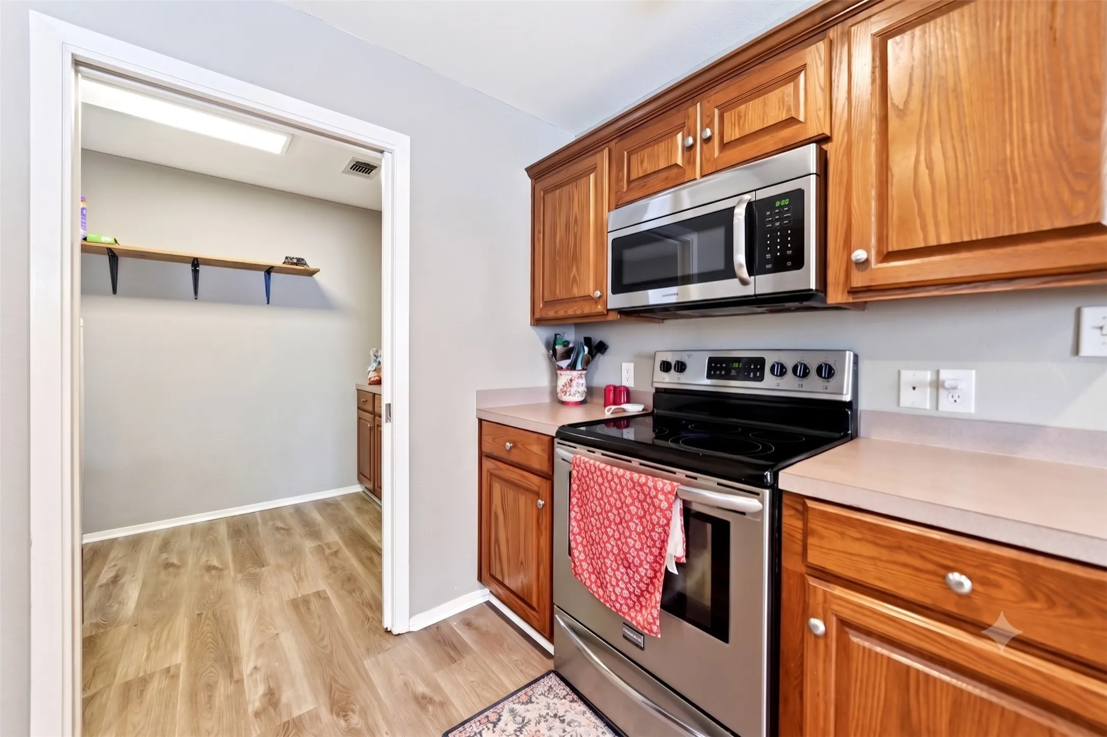 Kitchen featuring wood-finish cabinetry, light-toned countertops, and stainless steel appliances