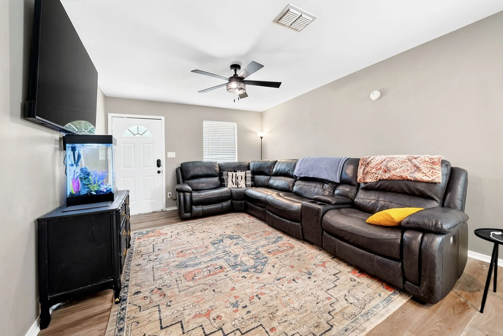 Living area featuring light wood-finish flooring, neutral-toned walls, and a ceiling fan