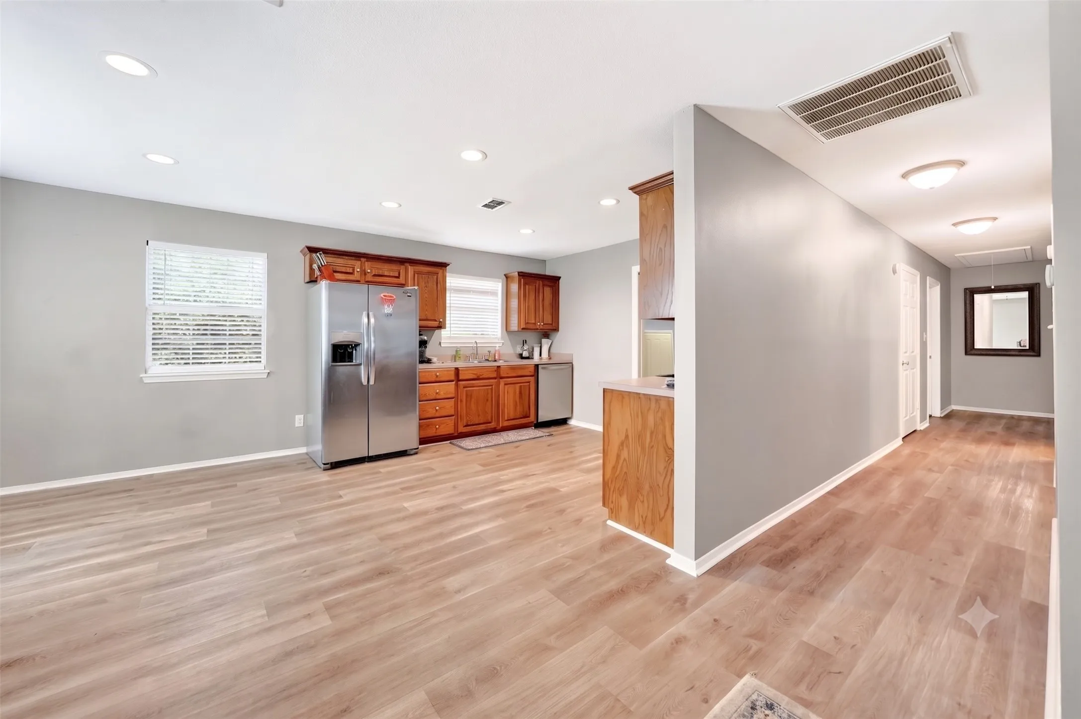 Open-concept living space featuring wood-finish flooring, recessed ceiling lights, and contemporary gray wall paint