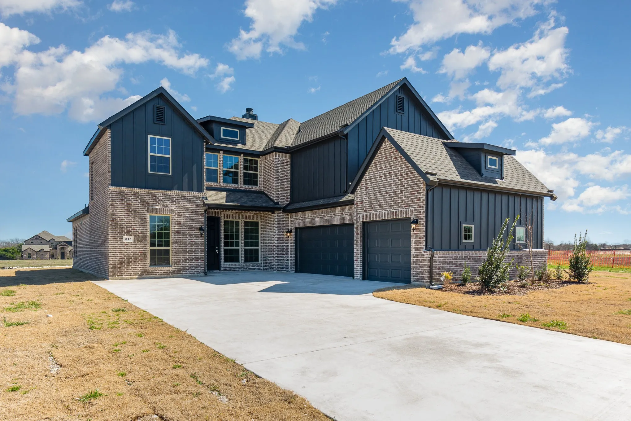 Contemporary two-story residence featuring a brick and vertical siding exterior, a two-car garage, a concrete driveway, and a gabled roofline