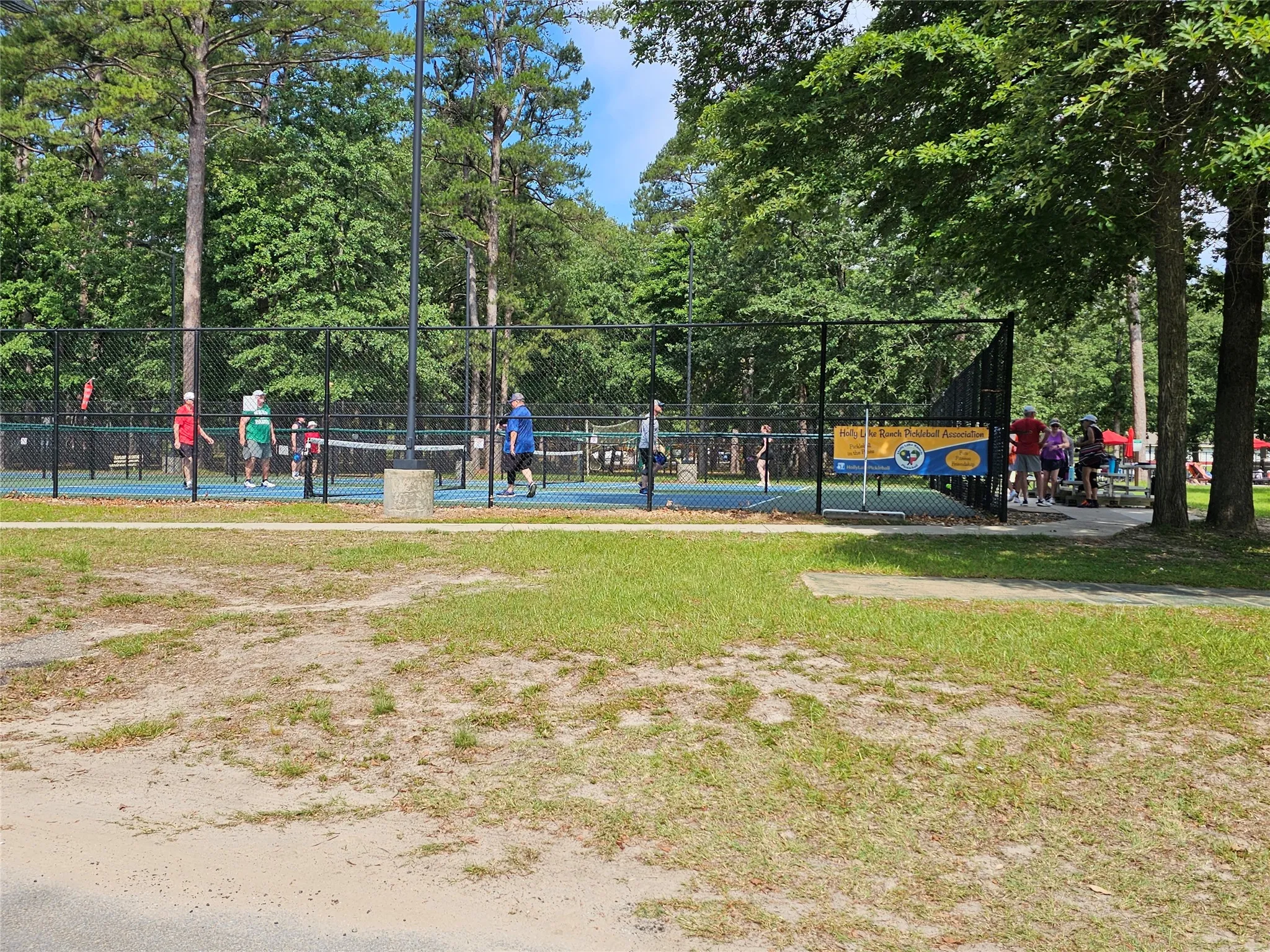 Outdoor recreational courts with blue surfaces, surrounded by black chain-link fencing
