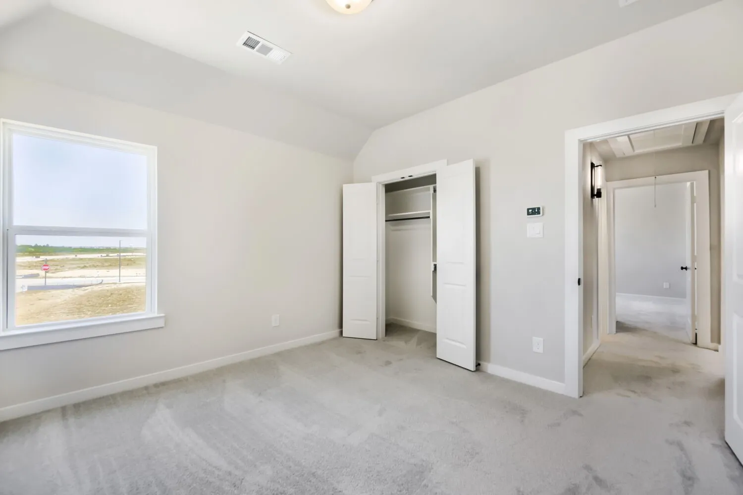 Recessed lighting, light gray carpeting, ample natural light from a large window, bi-fold closet doors, and neutral wall paint
