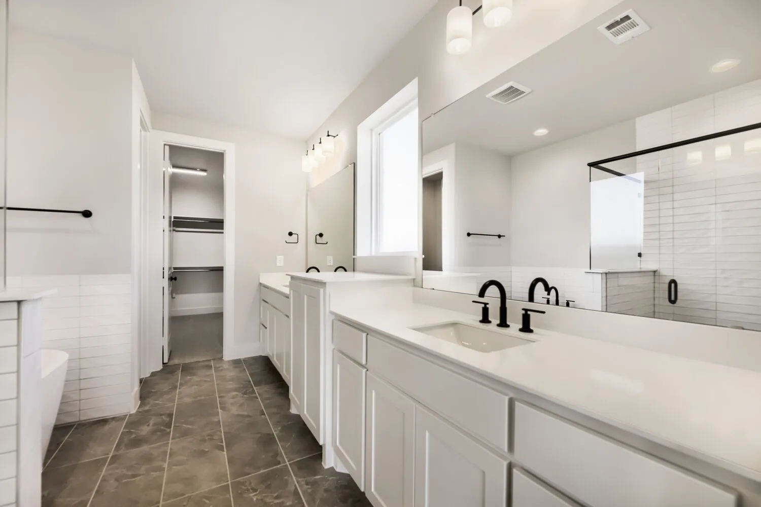 Dual vanity with white cabinetry, integrated sinks, and black fixtures