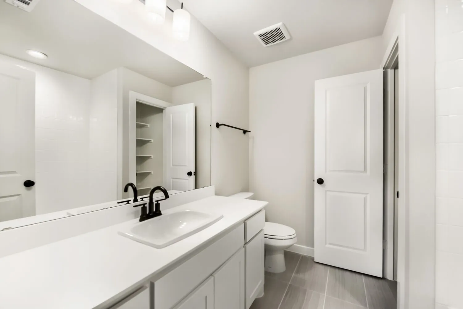 White vanity with integrated rectangular sink, matte black faucet, and expansive wall mirror
