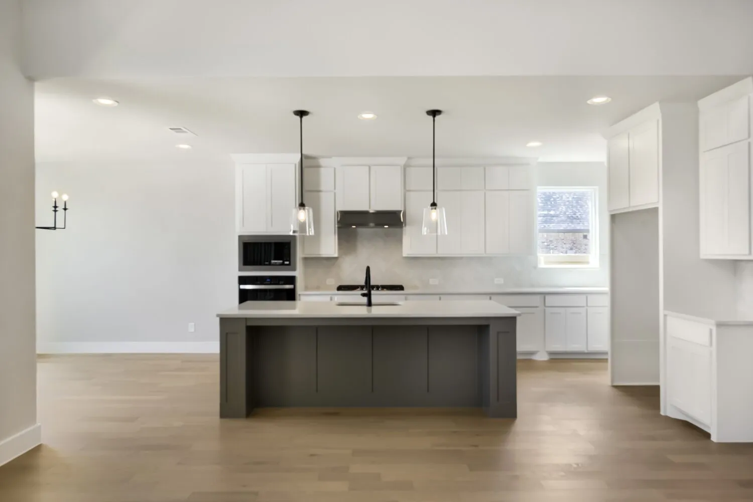 Open-concept kitchen with a two-tone island, pendant lighting, built-in oven, and wood-finish flooring