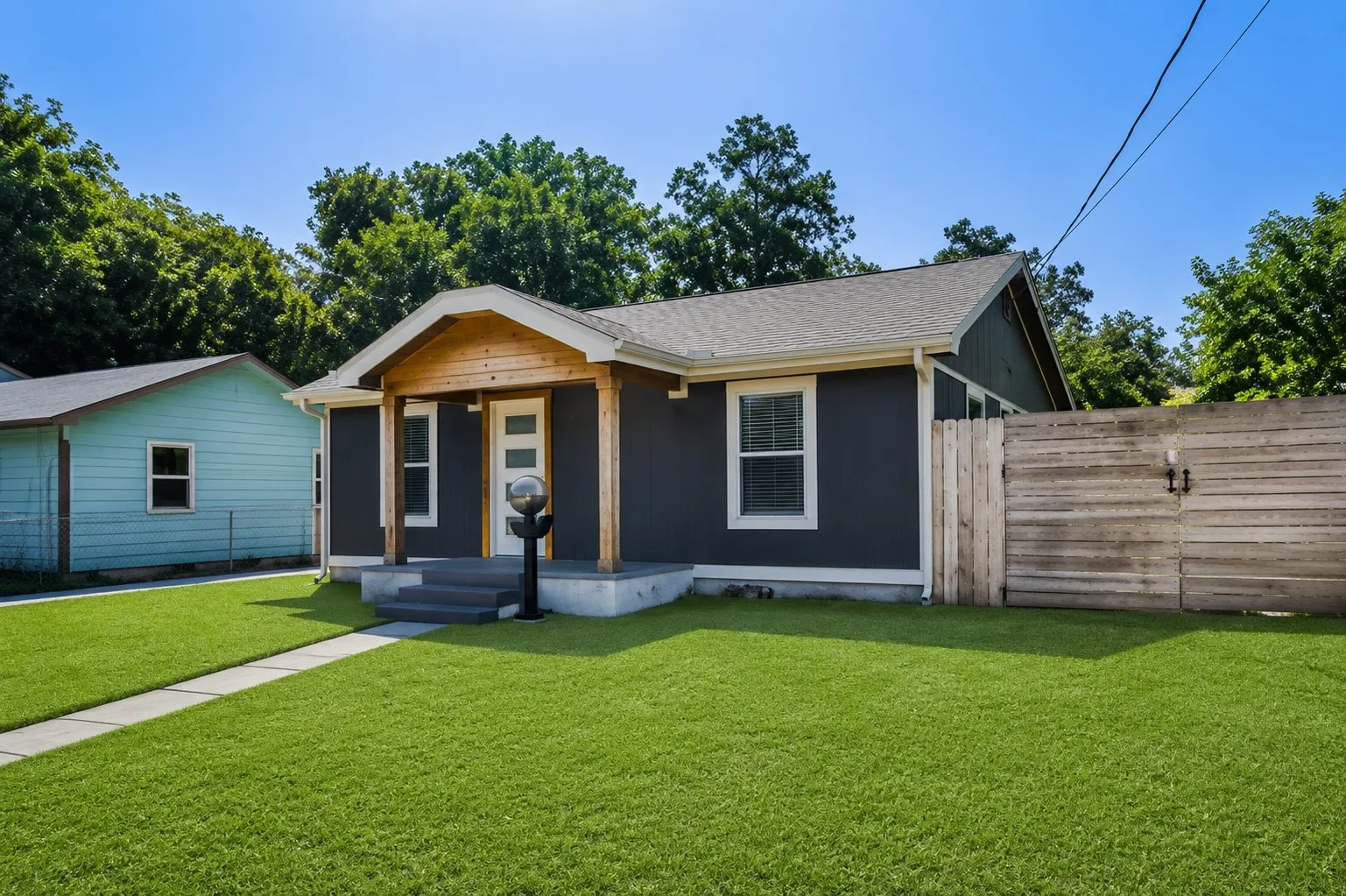 Contemporary exterior with dark siding, a light wood porch accent, and a light-colored entry door with frosted glass panels