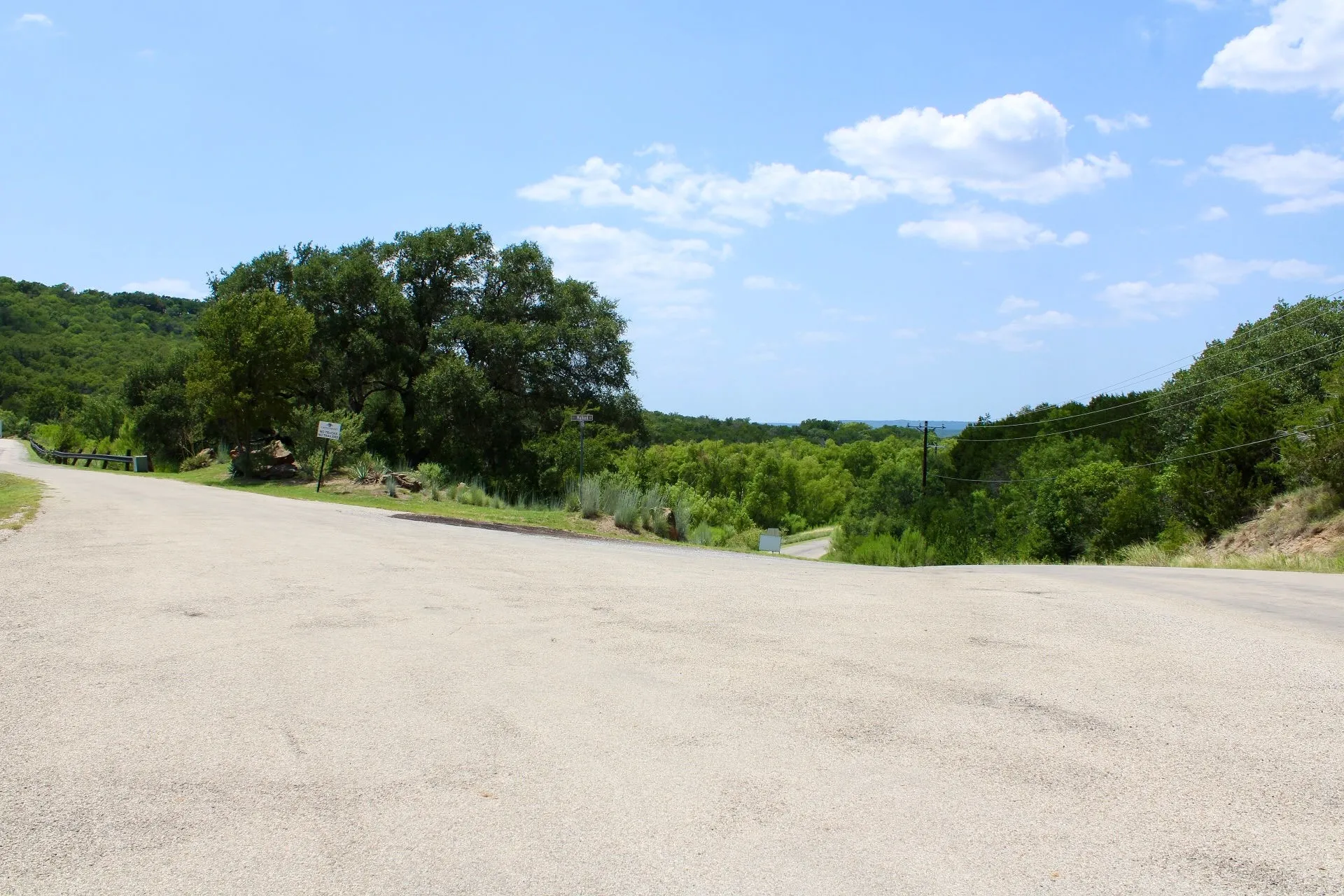 Paved road with expansive natural surroundings featuring mature trees and distant horizon