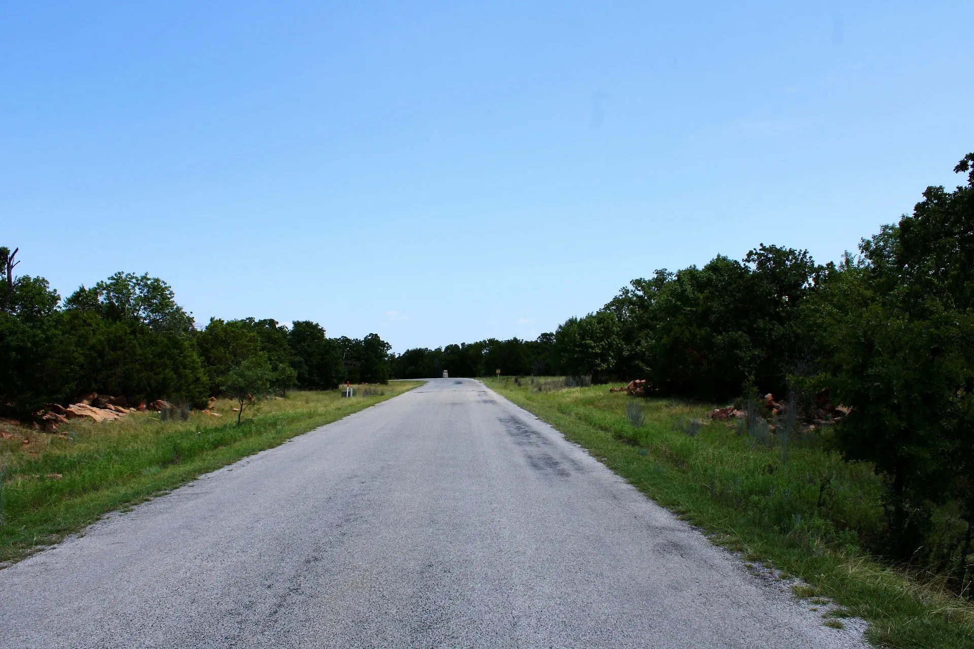 Paved roadway extending into the distance, bordered by green foliage and natural rock formations