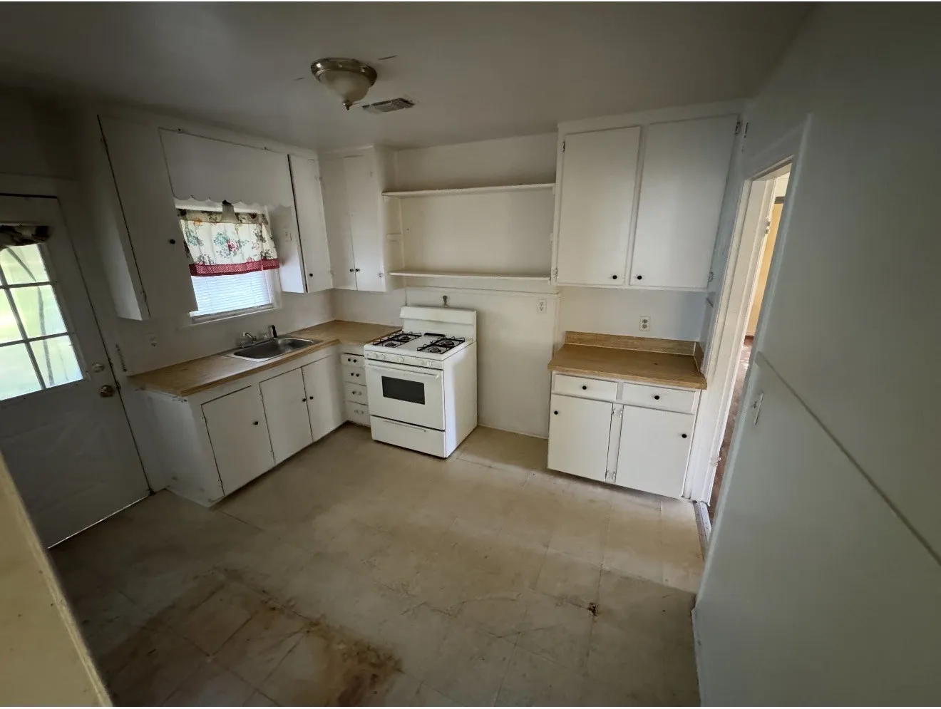 Efficient kitchen featuring white cabinetry, light-toned countertops, a gas range, and a single basin sink with window
