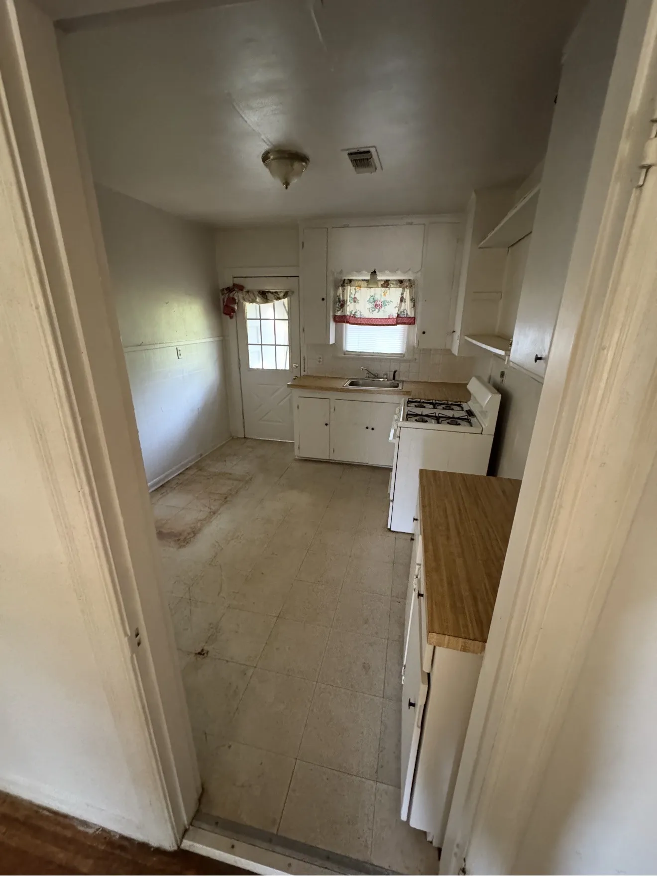 Kitchen featuring white cabinetry, light wood-finish countertops, and a gas range