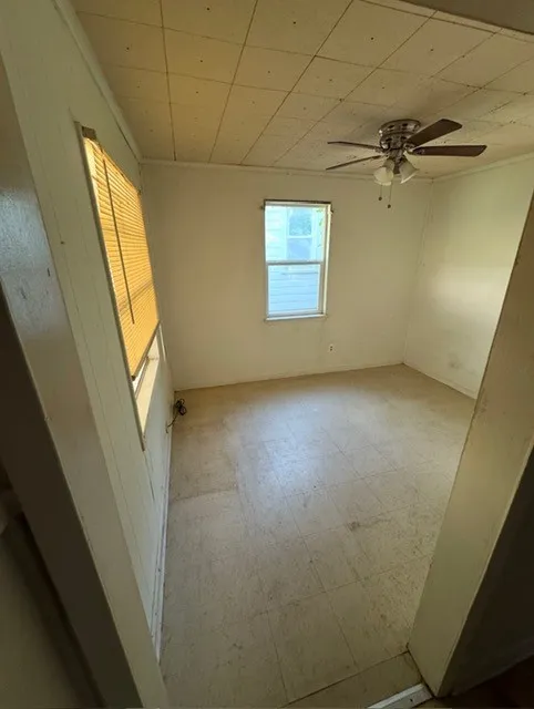 Room featuring two windows, one equipped with blinds, and a ceiling fan with integrated lighting
