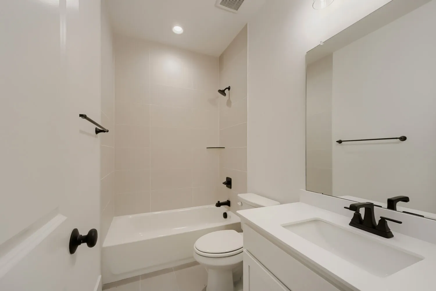 White vanity with an integrated sink, matte black faucet, and a large wall-mounted mirror