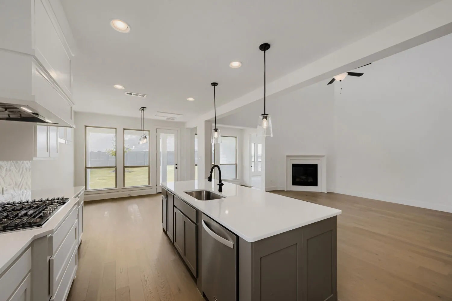 Kitchen island with integrated sink, stainless steel dishwasher, and pendant lighting