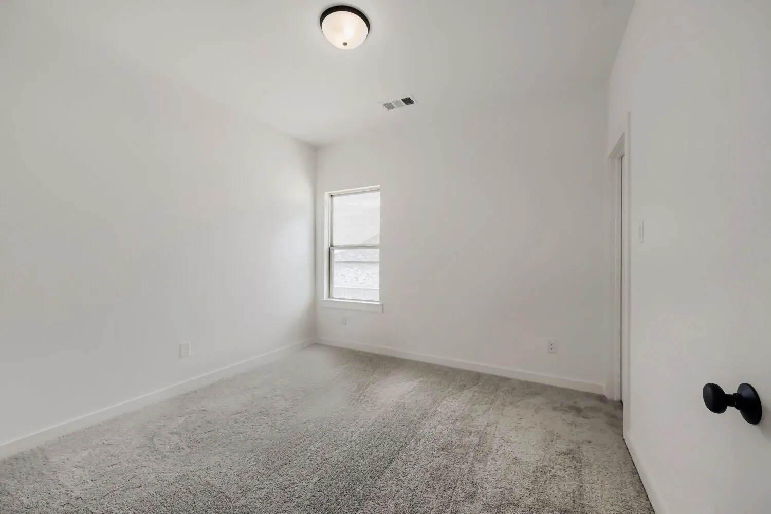 Recessed lighting, wall-to-wall carpeting, and a single window with white trim