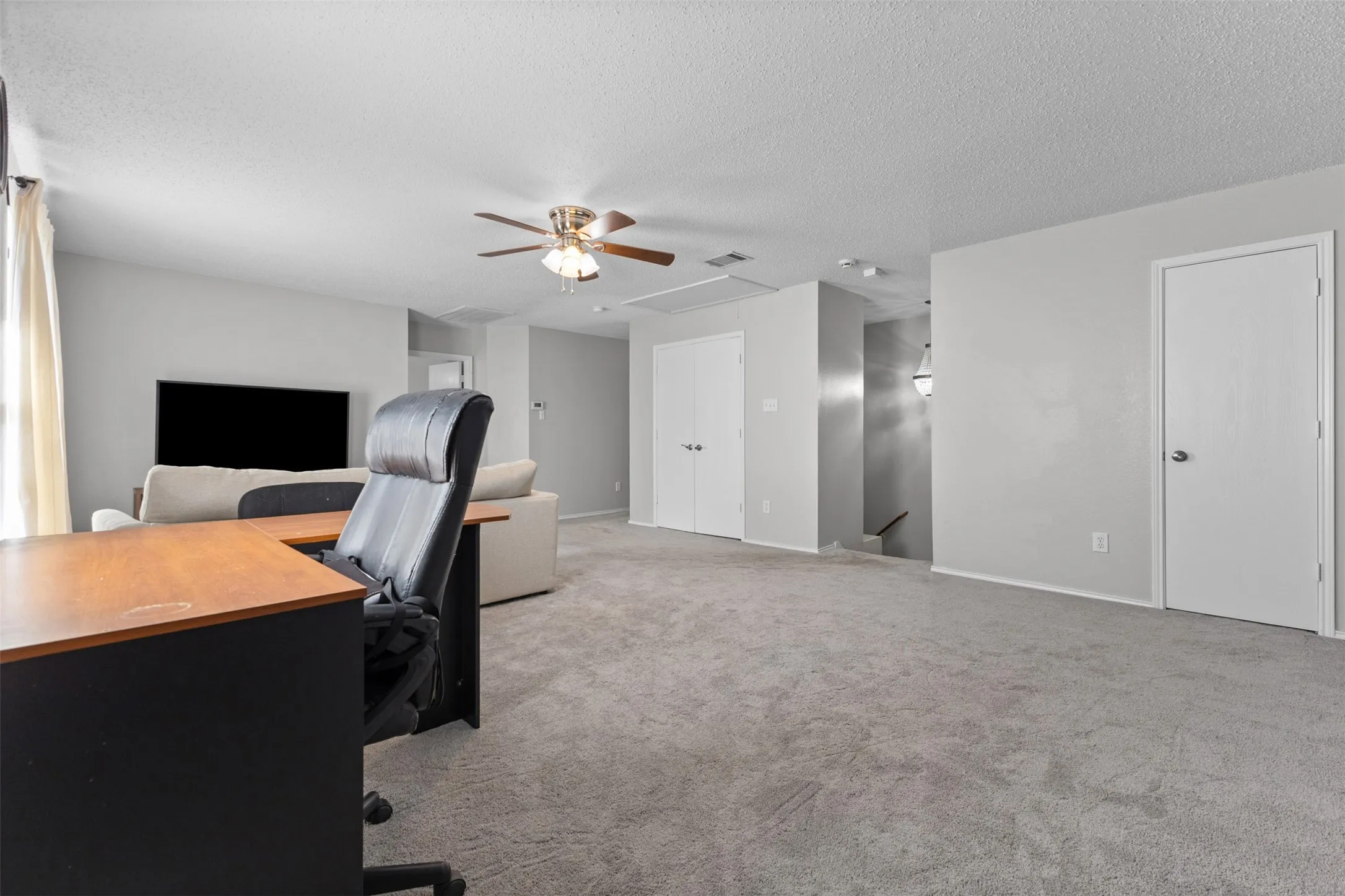 Open-concept living space with light gray wall paint and gray carpeting
