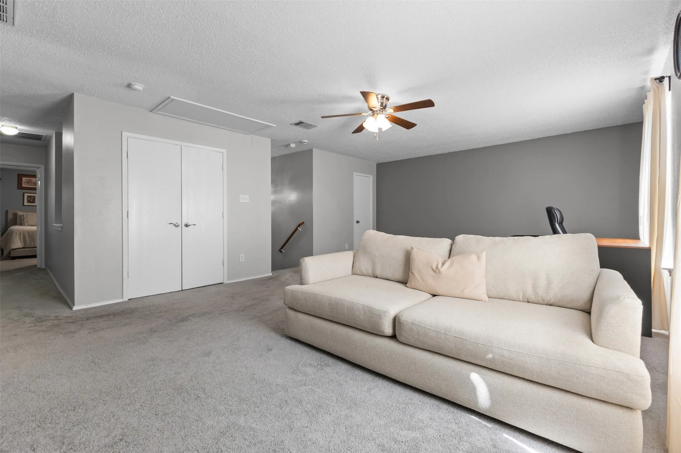 Spacious carpeted room featuring light gray walls and a contrasting dark accent wall
