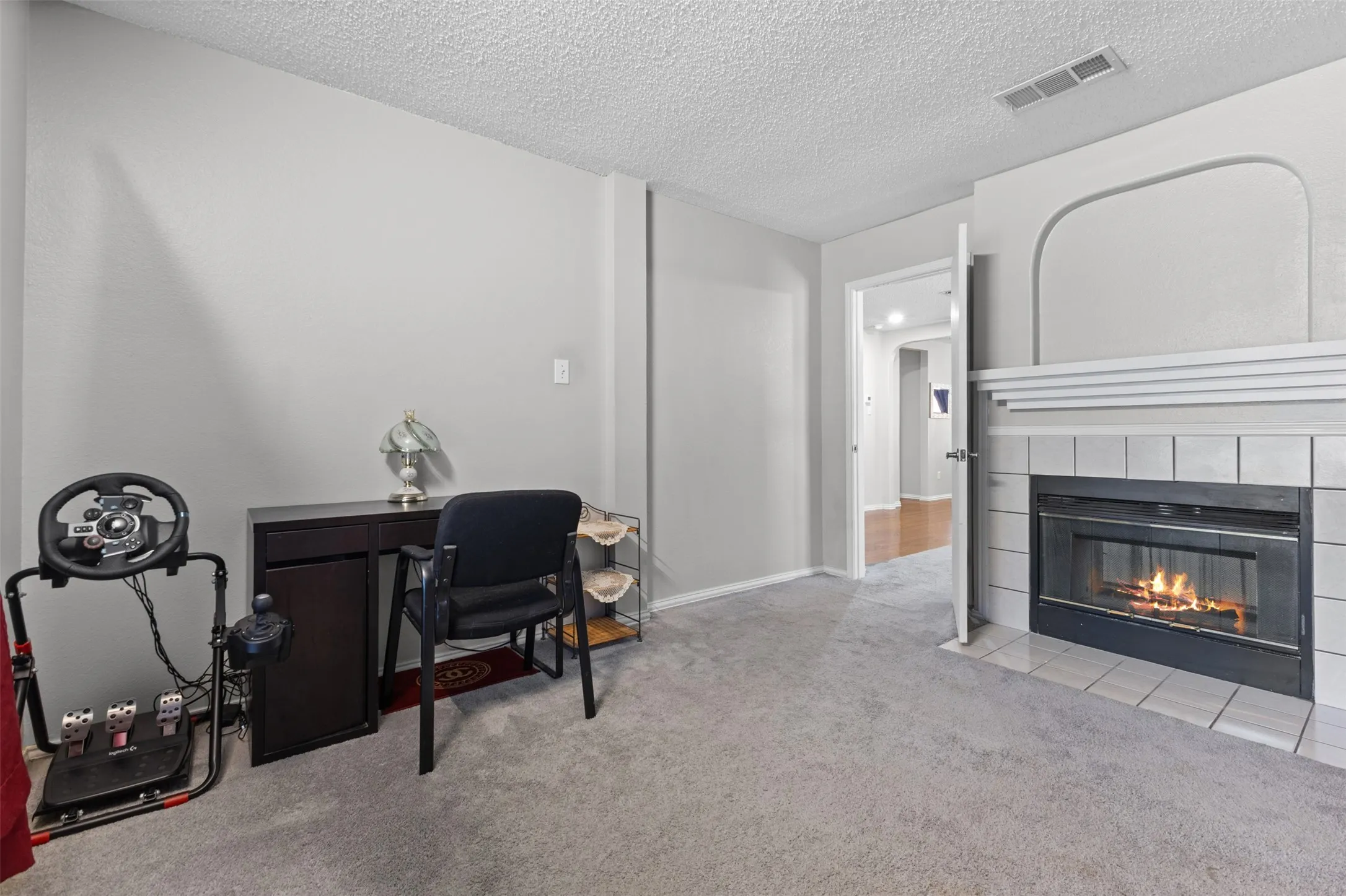 Carpeted room featuring a white tile fireplace with a mantel