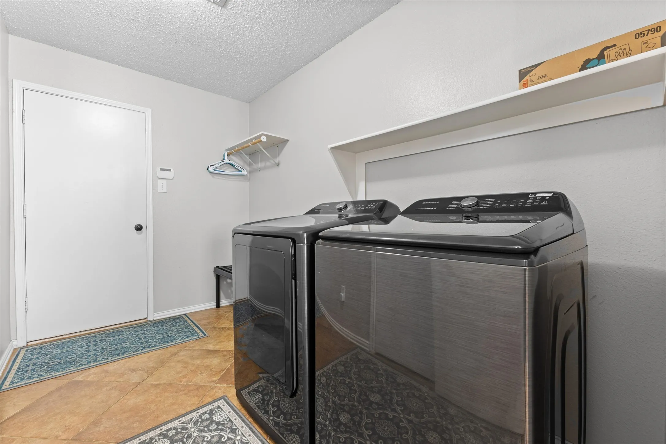 Dedicated utility space featuring a neutral color palette, ceramic tile flooring, and a full-size washer and dryer