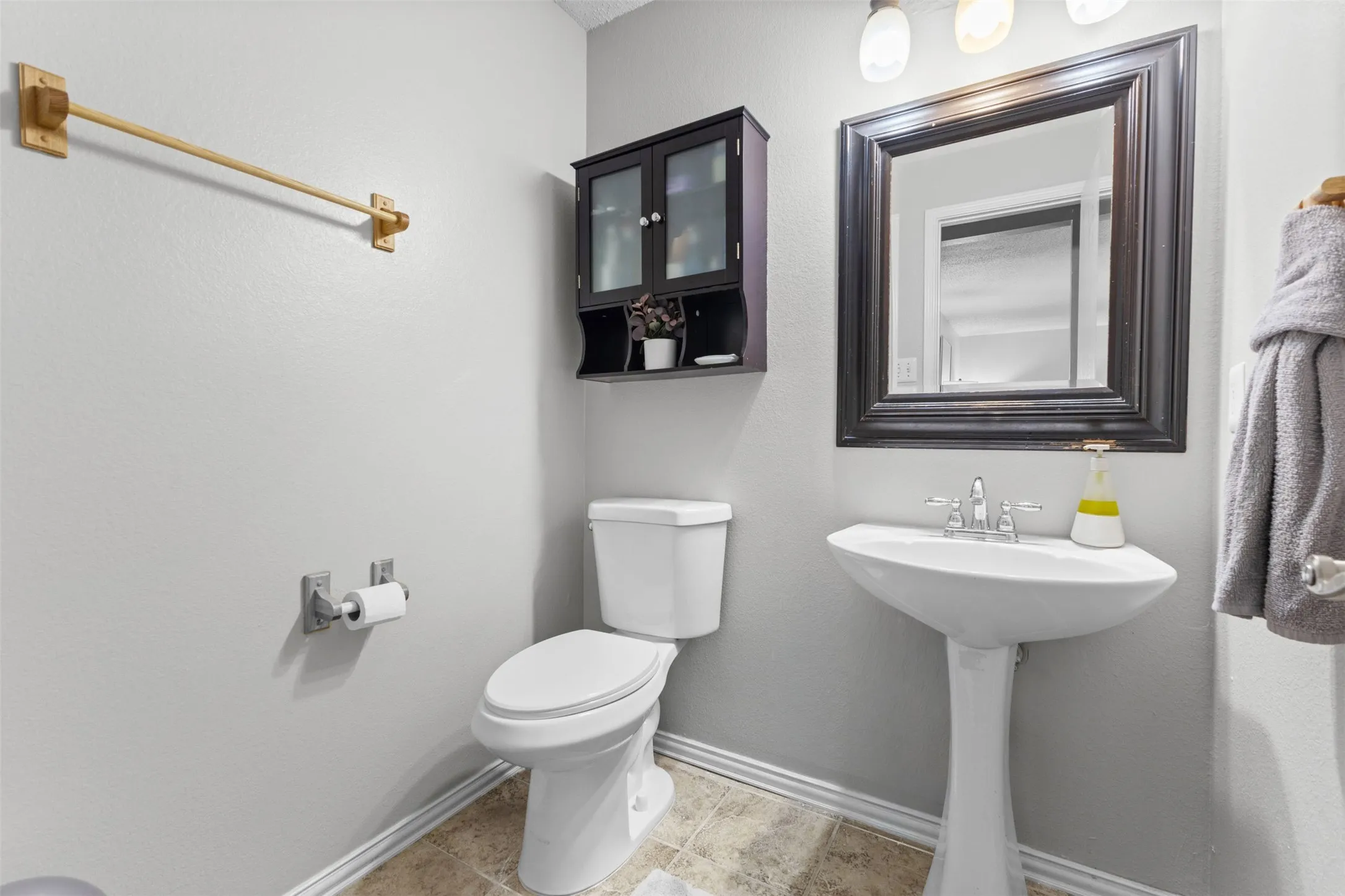 Pedestal sink vanity with chrome faucet, framed mirror, and three-light fixture