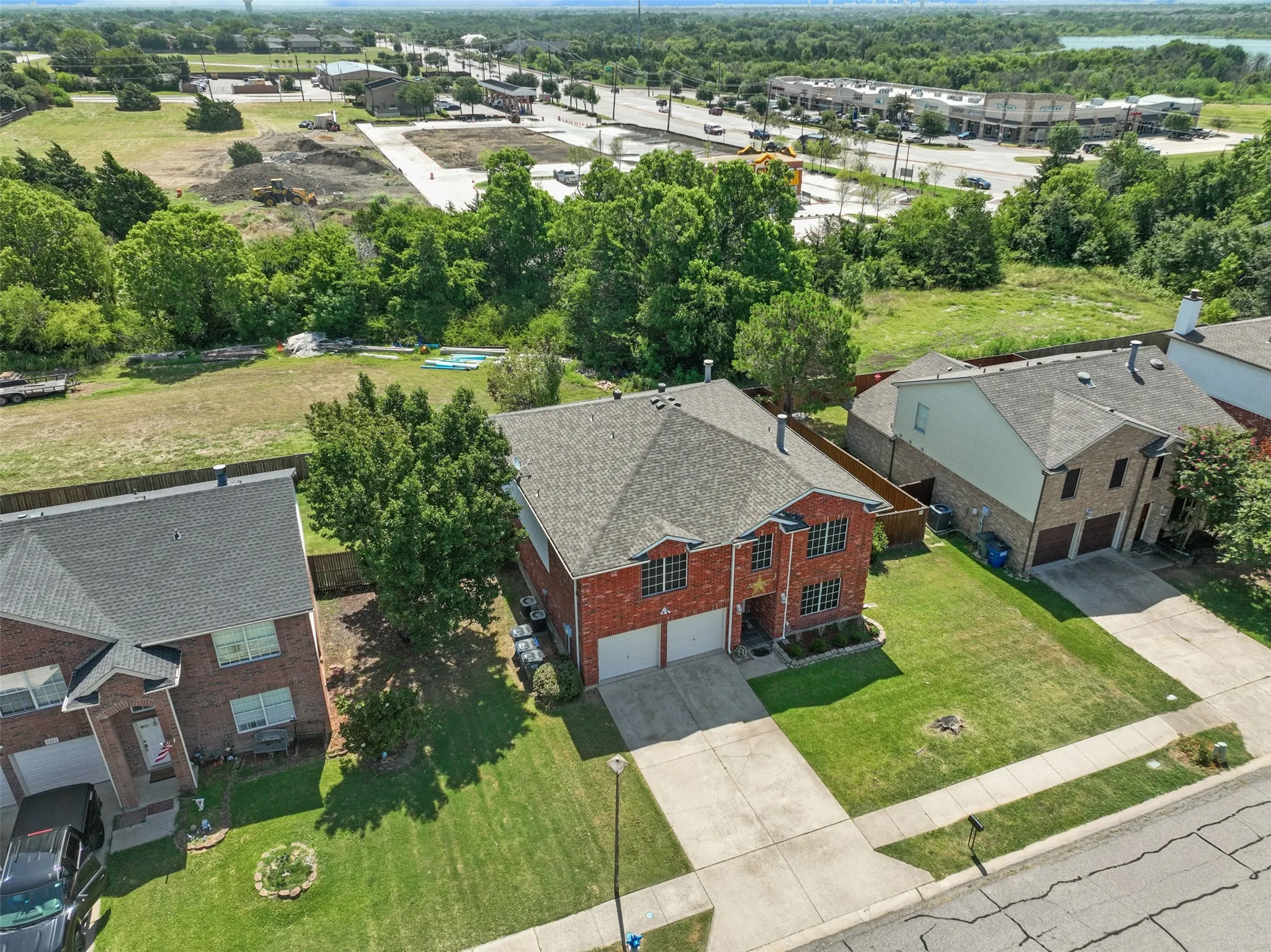 Brick facade residence featuring a two-car garage, dark shingle roof, and a green lawn
