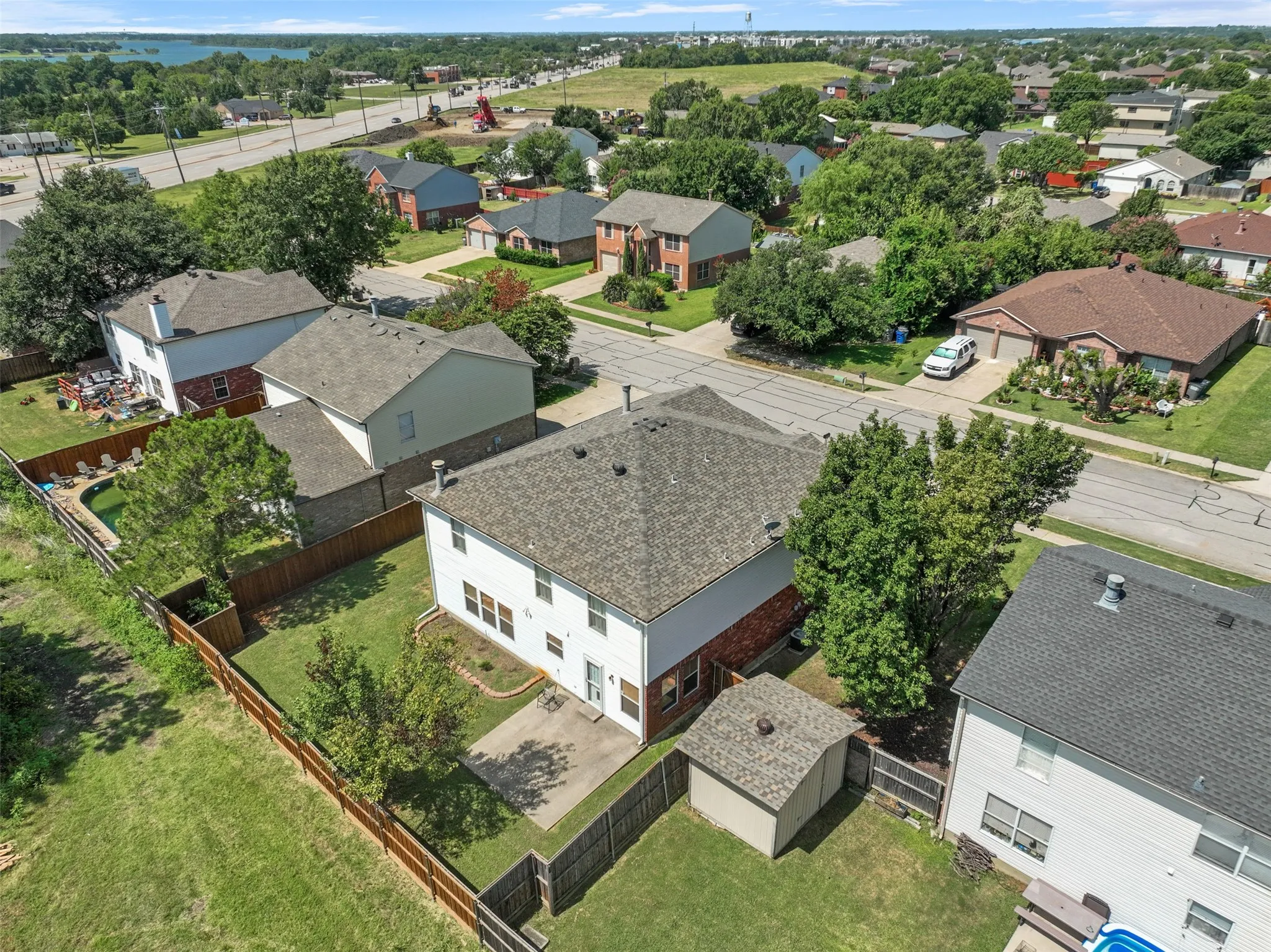Two-story residence with a gray shingle roof, featuring a private fenced backyard