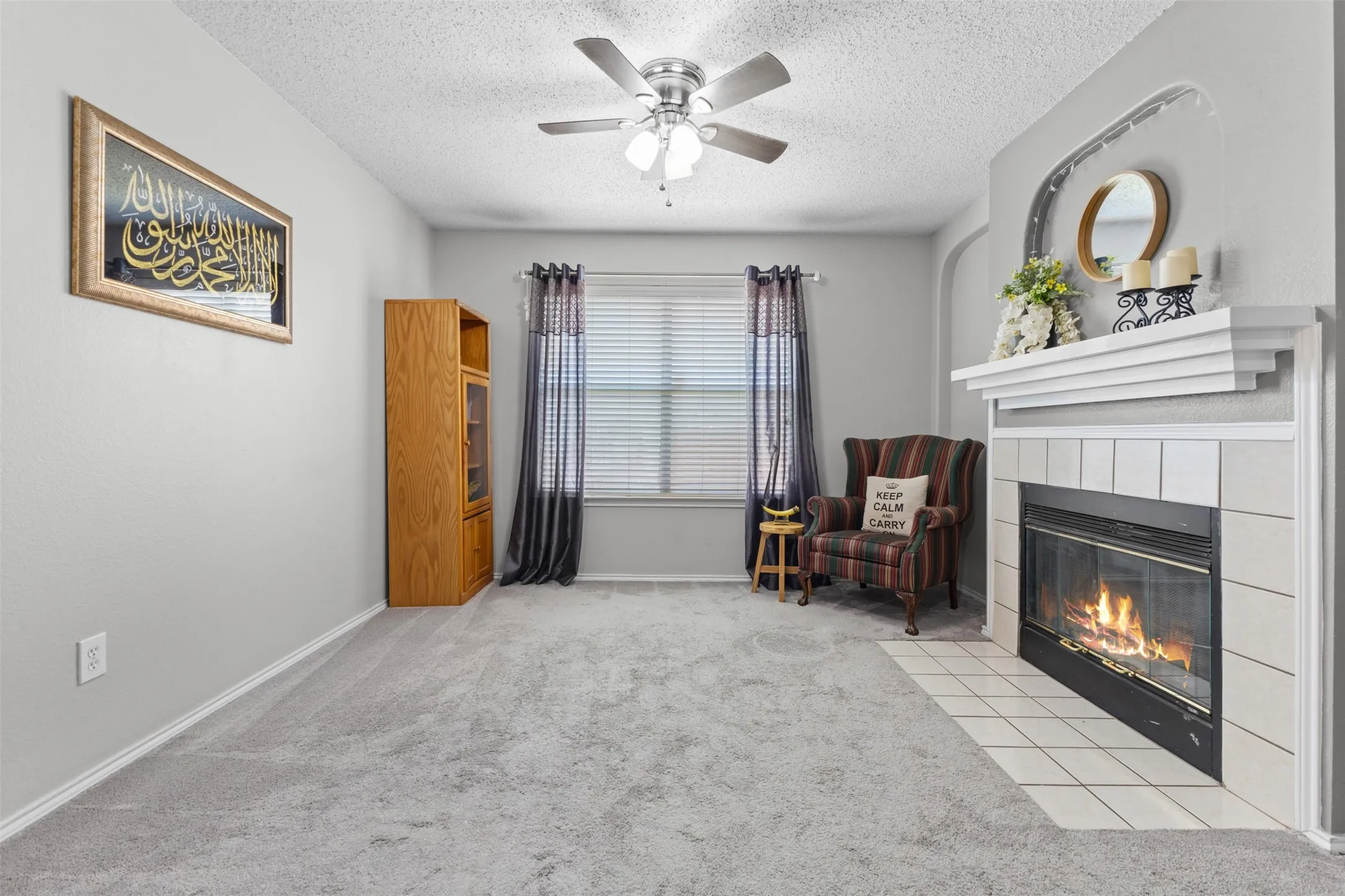 Living area featuring a fireplace with a white tile surround and a decorative mantel