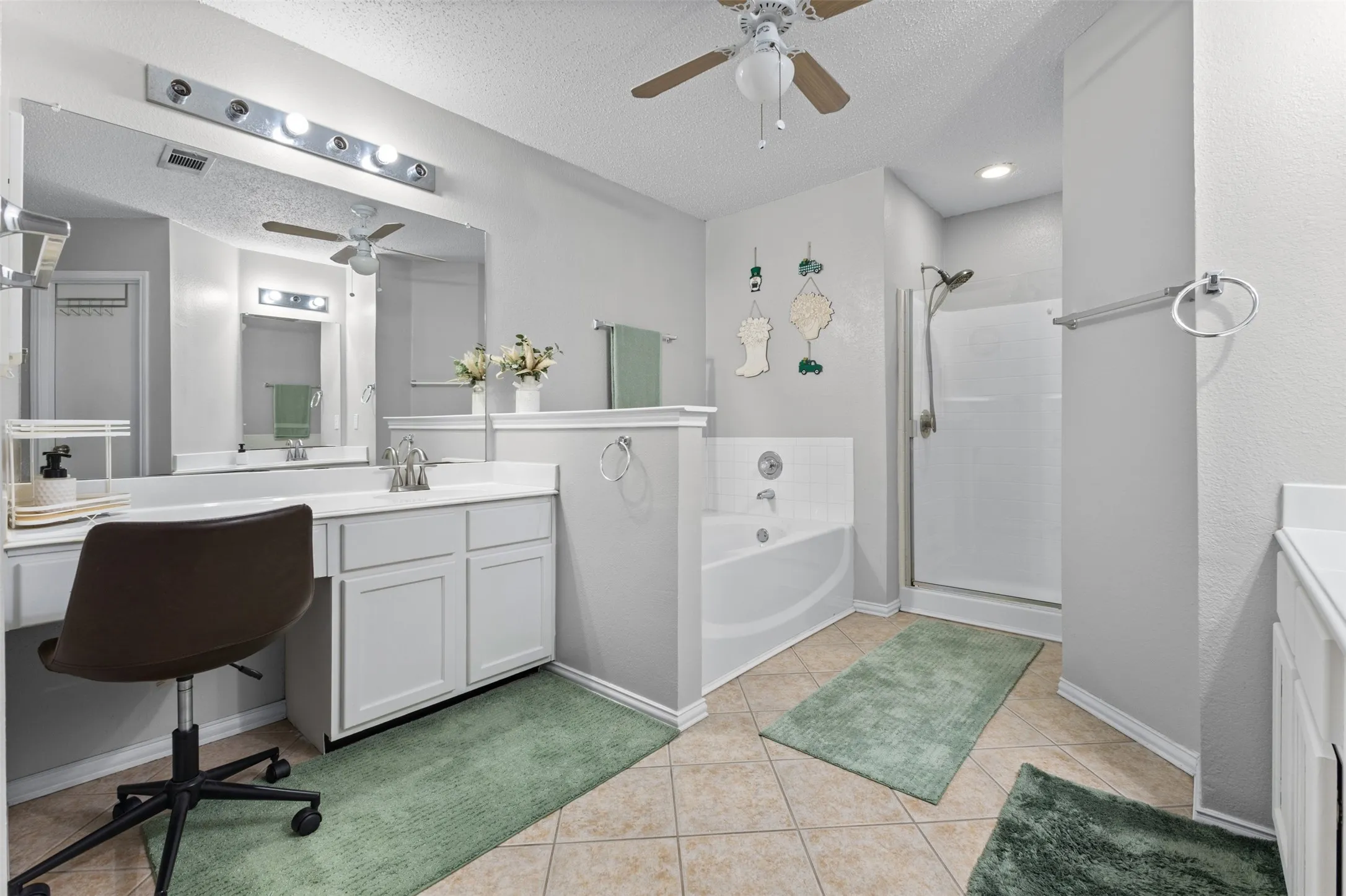 Spacious bathroom featuring a dual vanity with integrated sink, white cabinetry, and a large wall-mounted mirror
