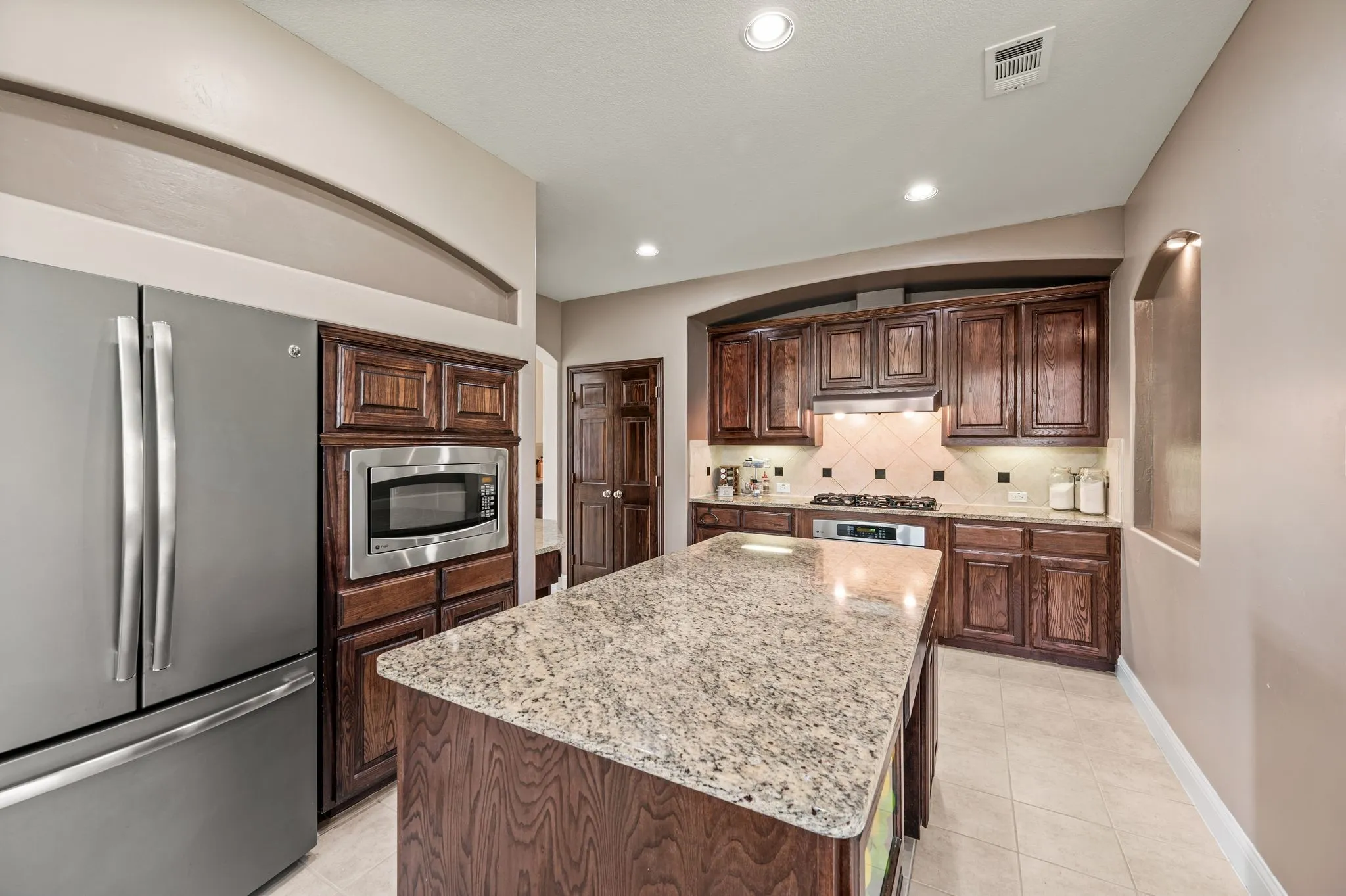 Large center island provides plenty of prep space while overlooking the main living area. Notice the under-cabinet lighting in the distance!