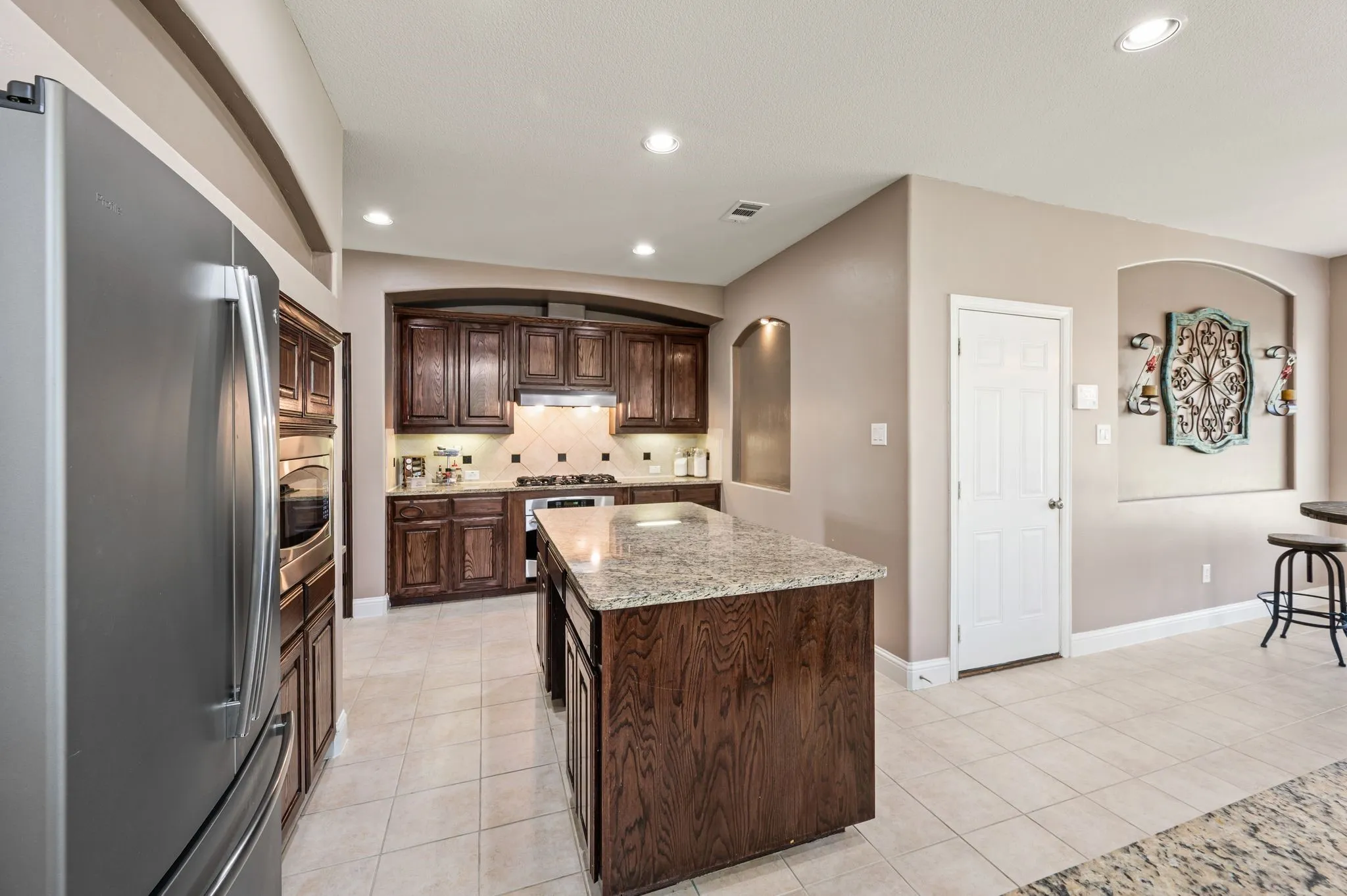 This spacious kitchen features a HUGE island with bar height seating options in the middle and electricity present at the far end.  The kitchen boasts granite countertops, rich wood cabinetry &stainless steel appliances!