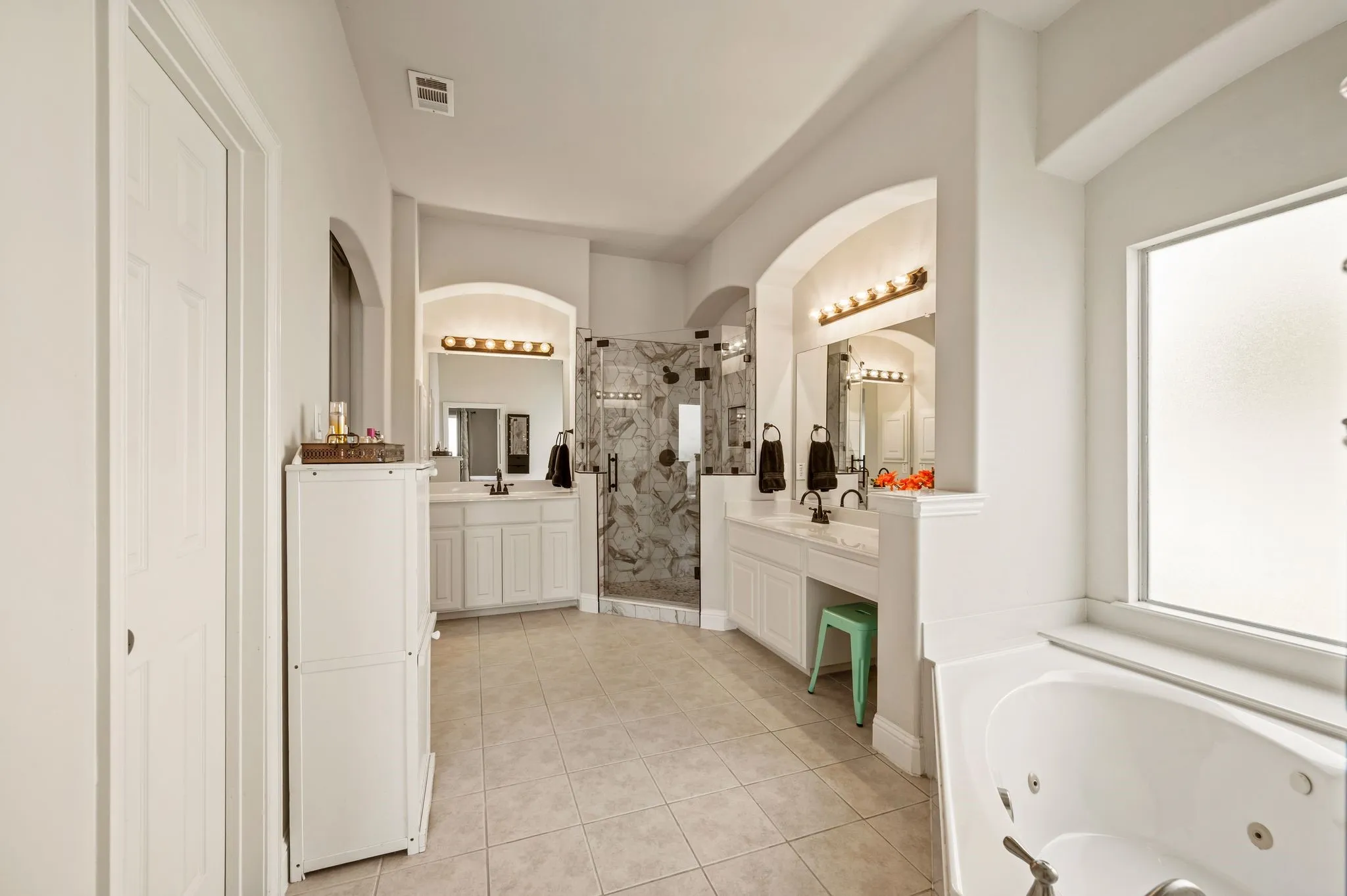 Spa-inspired primary bath features dual vanities (2 different heights), a large, jetted corner tub, oversized custom walk-in shower that was renovated in 2025 & an abundant space!