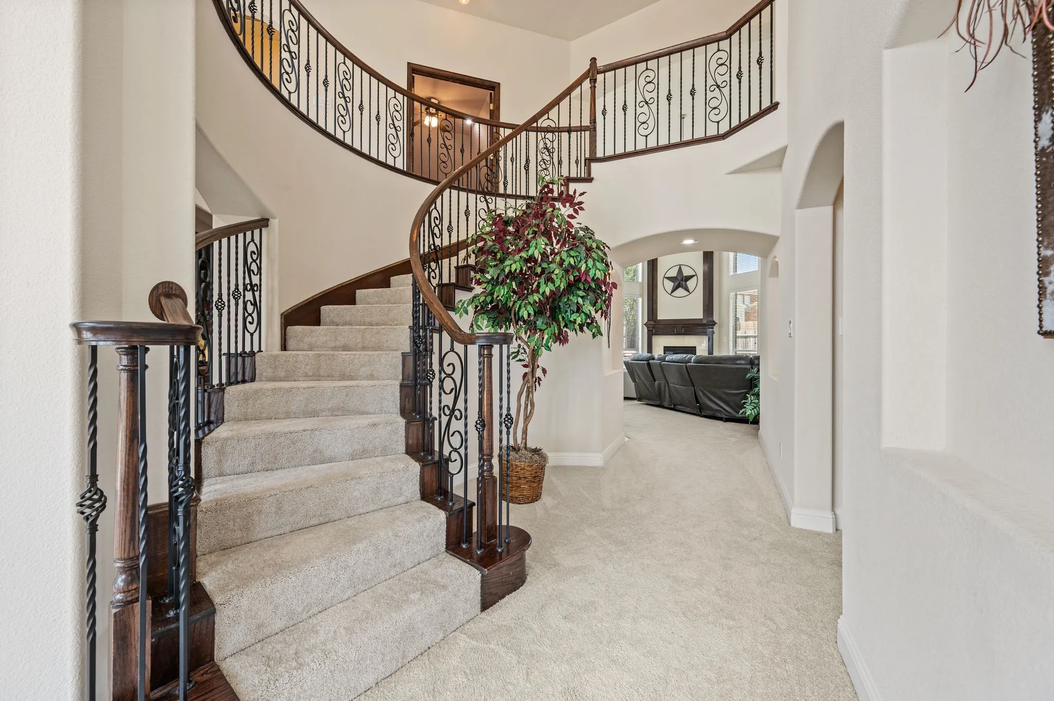 Elegant curved staircase & wrought iron railing create a dramatic first impression filled with architectural charm.