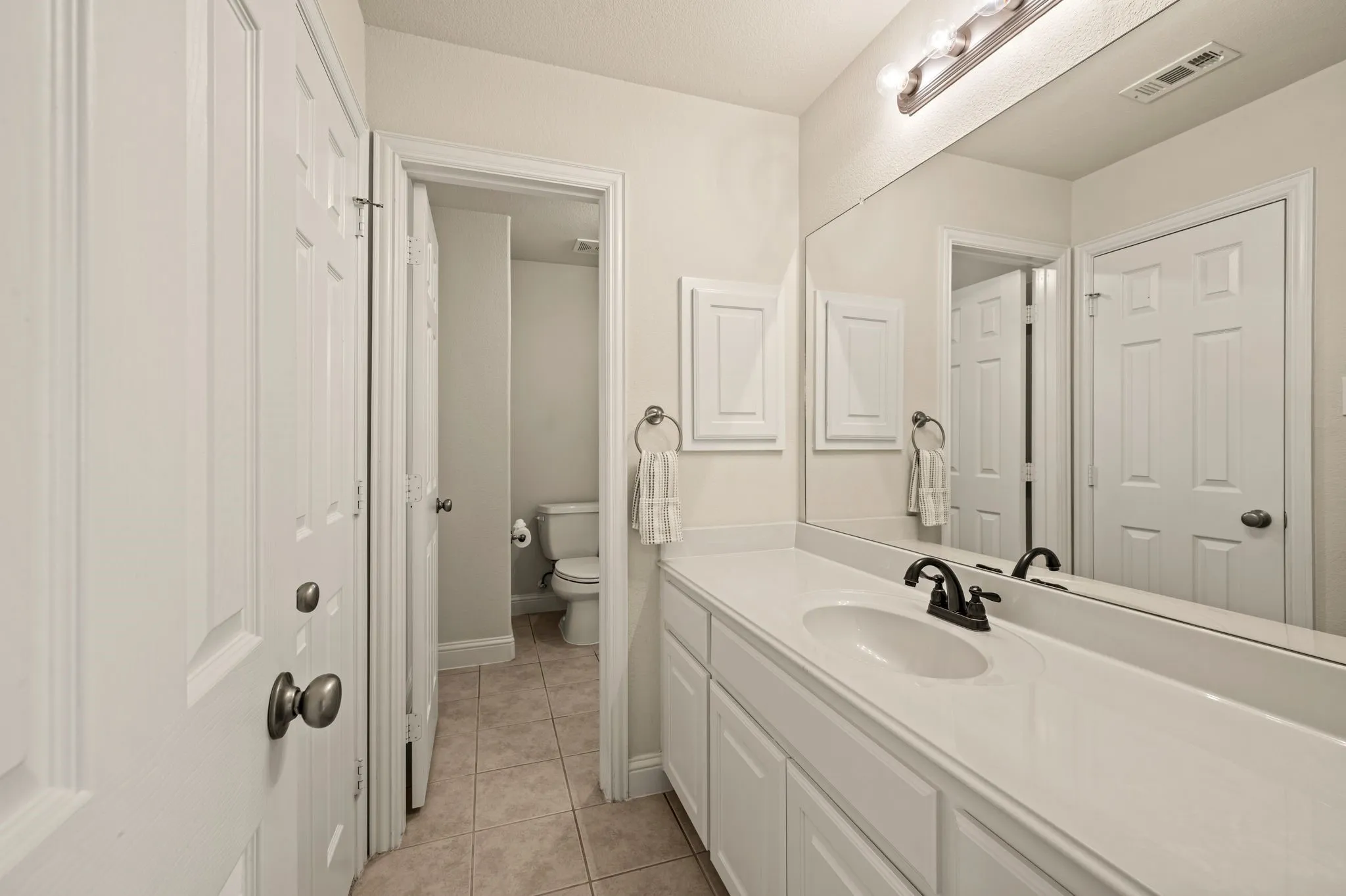 Well-appointed Jack-and-Jill style vanity with generous counter space & direct access to the adjoining bath.