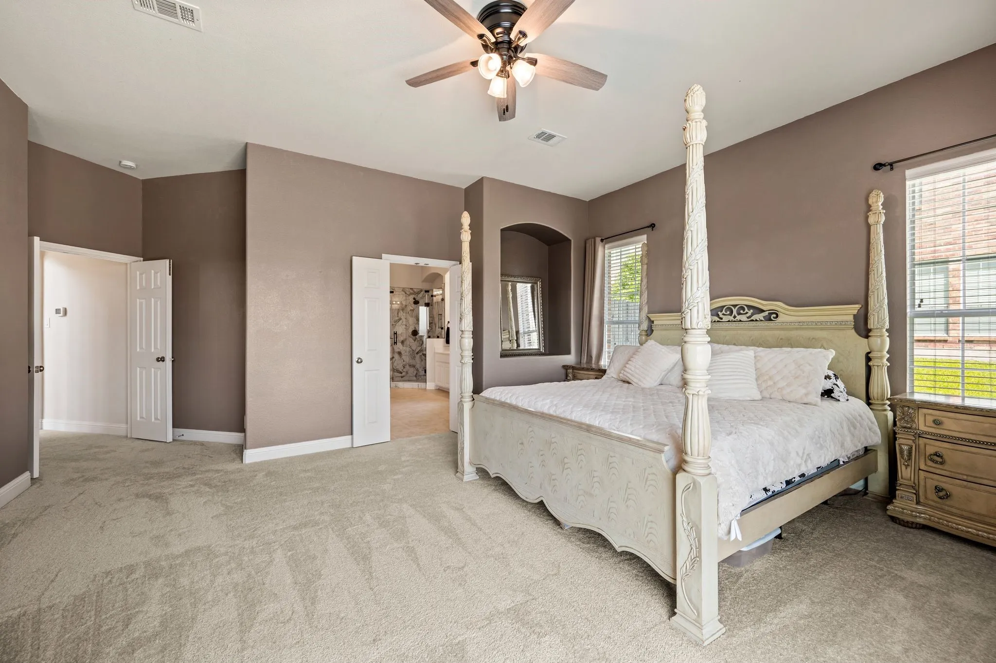 Another view of the luxurious primary bedroom highlighting its generous size & natural light.
