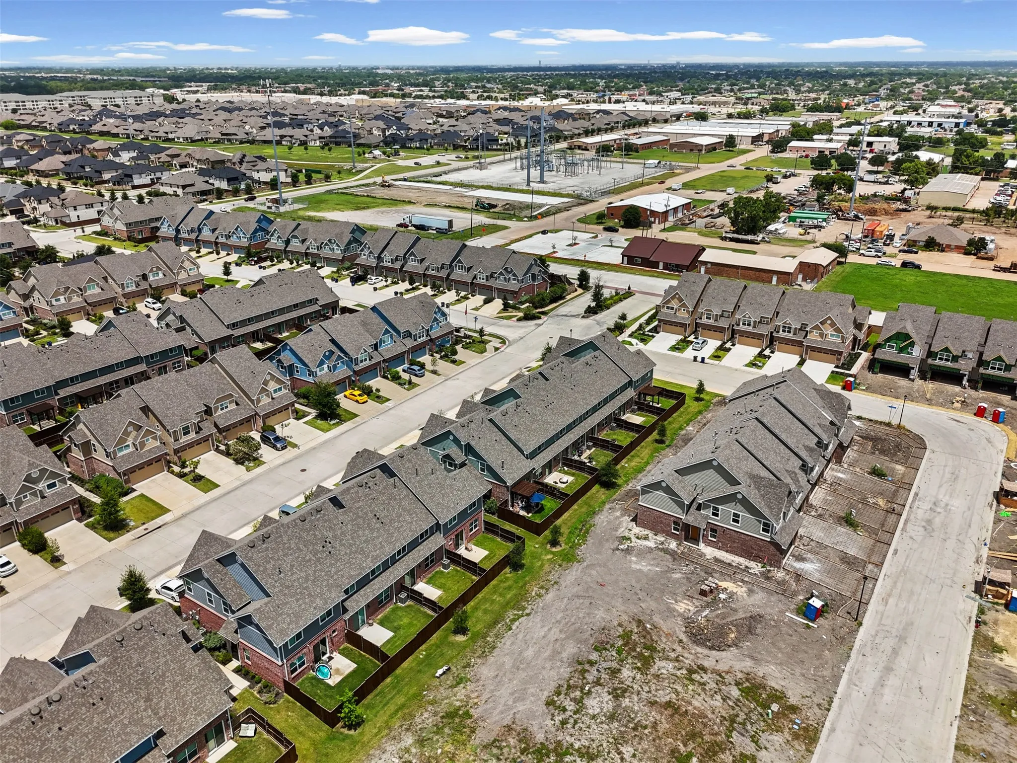 Aerial perspective showcasing multiple rows of townhomes with pitched roofs and individual yards