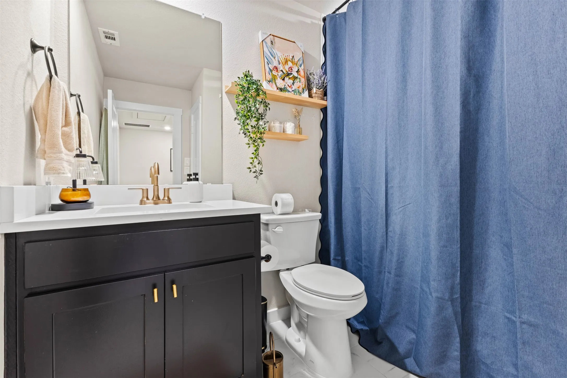 Bathroom featuring a black vanity with gold hardware, white countertop, and gold-finish faucet