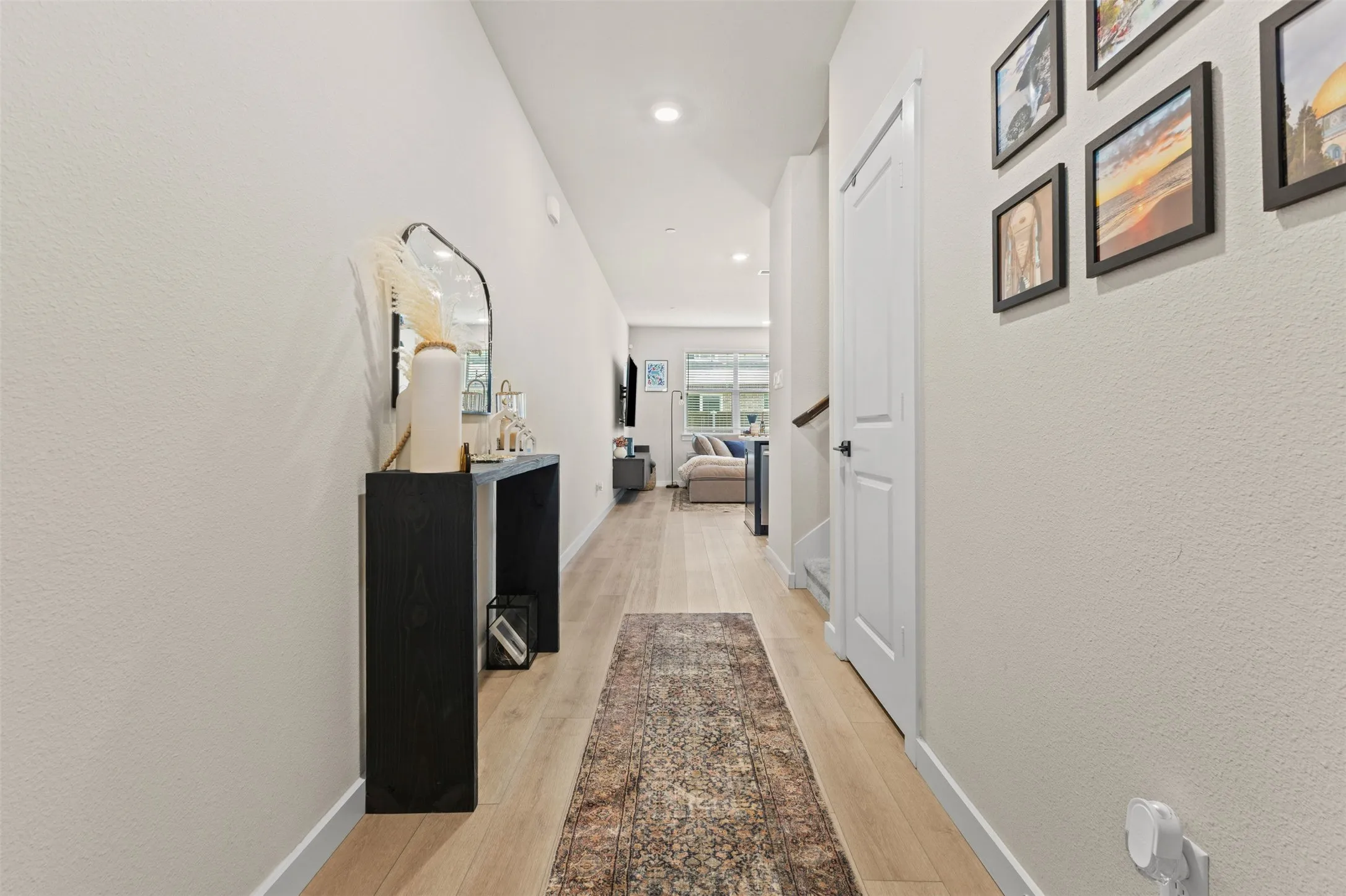 Long entryway featuring wood-finish flooring, recessed lighting, and a white interior door