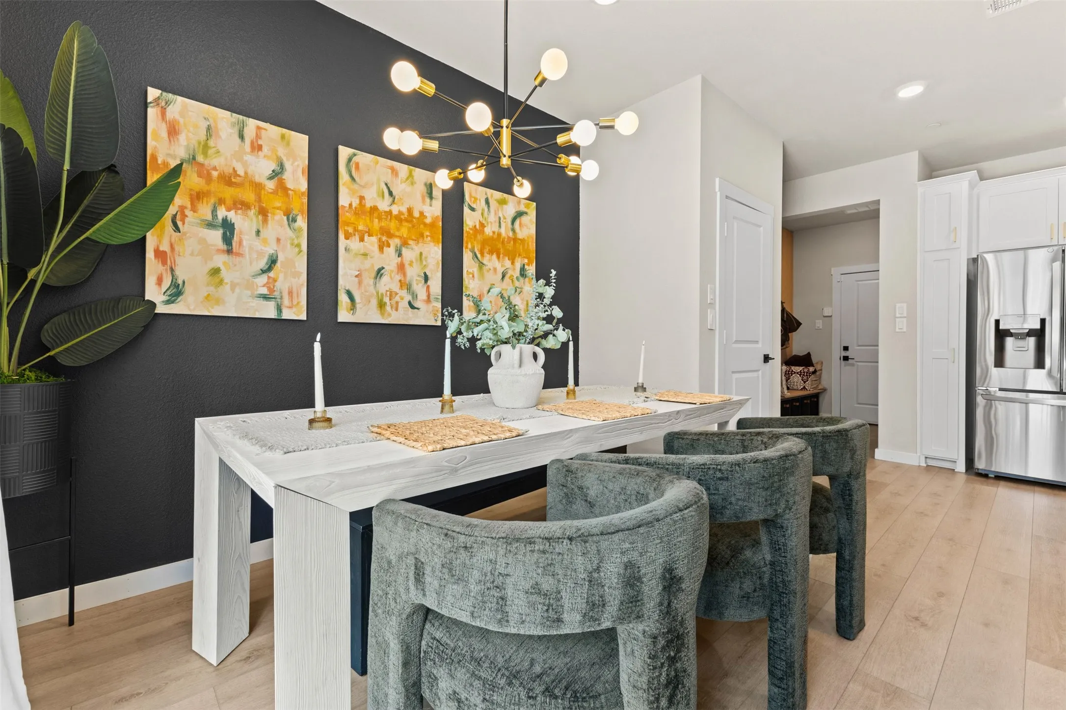 Dining area featuring a modern linear chandelier, wood-finish flooring, and a dark accent wall