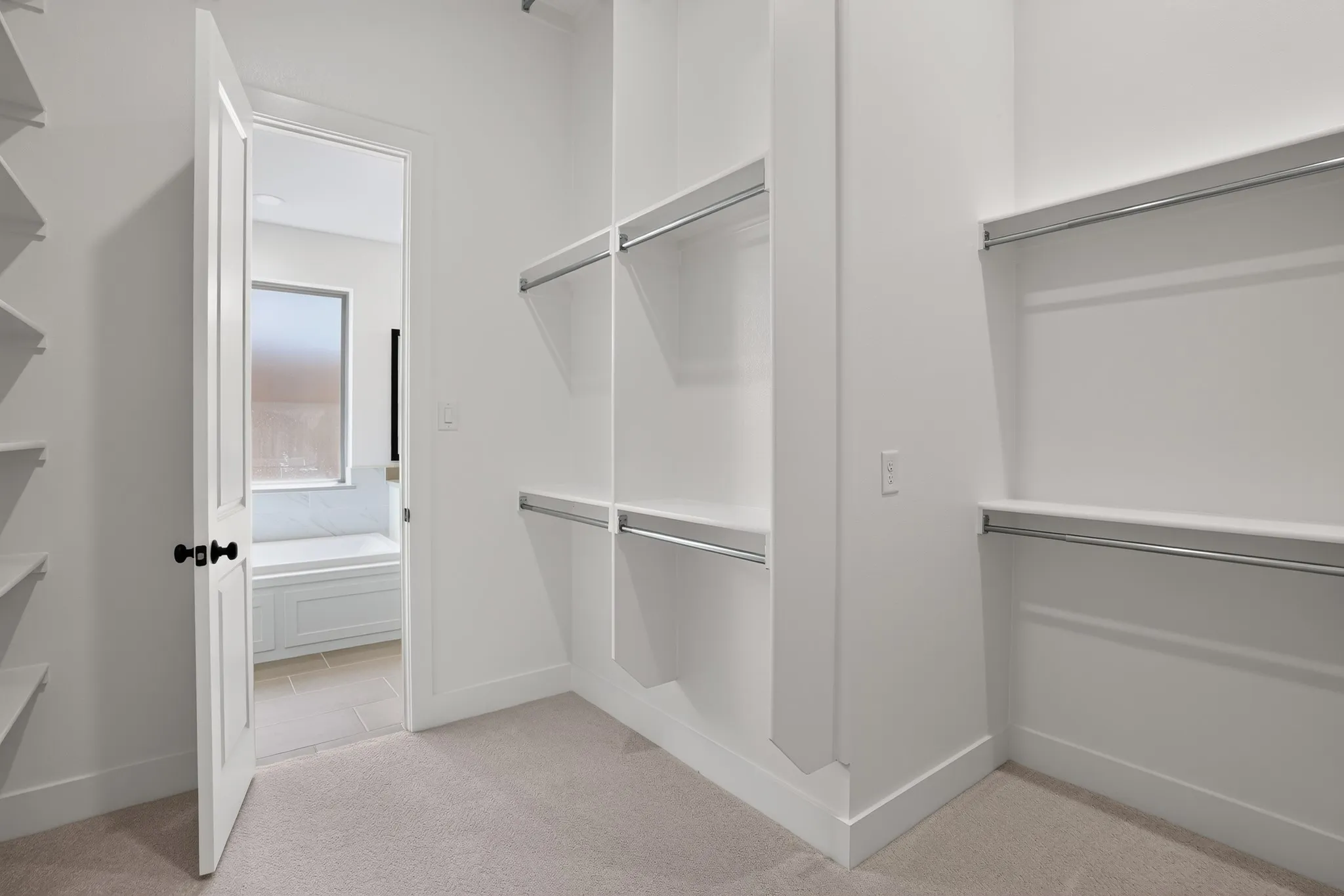 Walk-in closet featuring built-in shelving, chrome hanging rods, and neutral carpeting