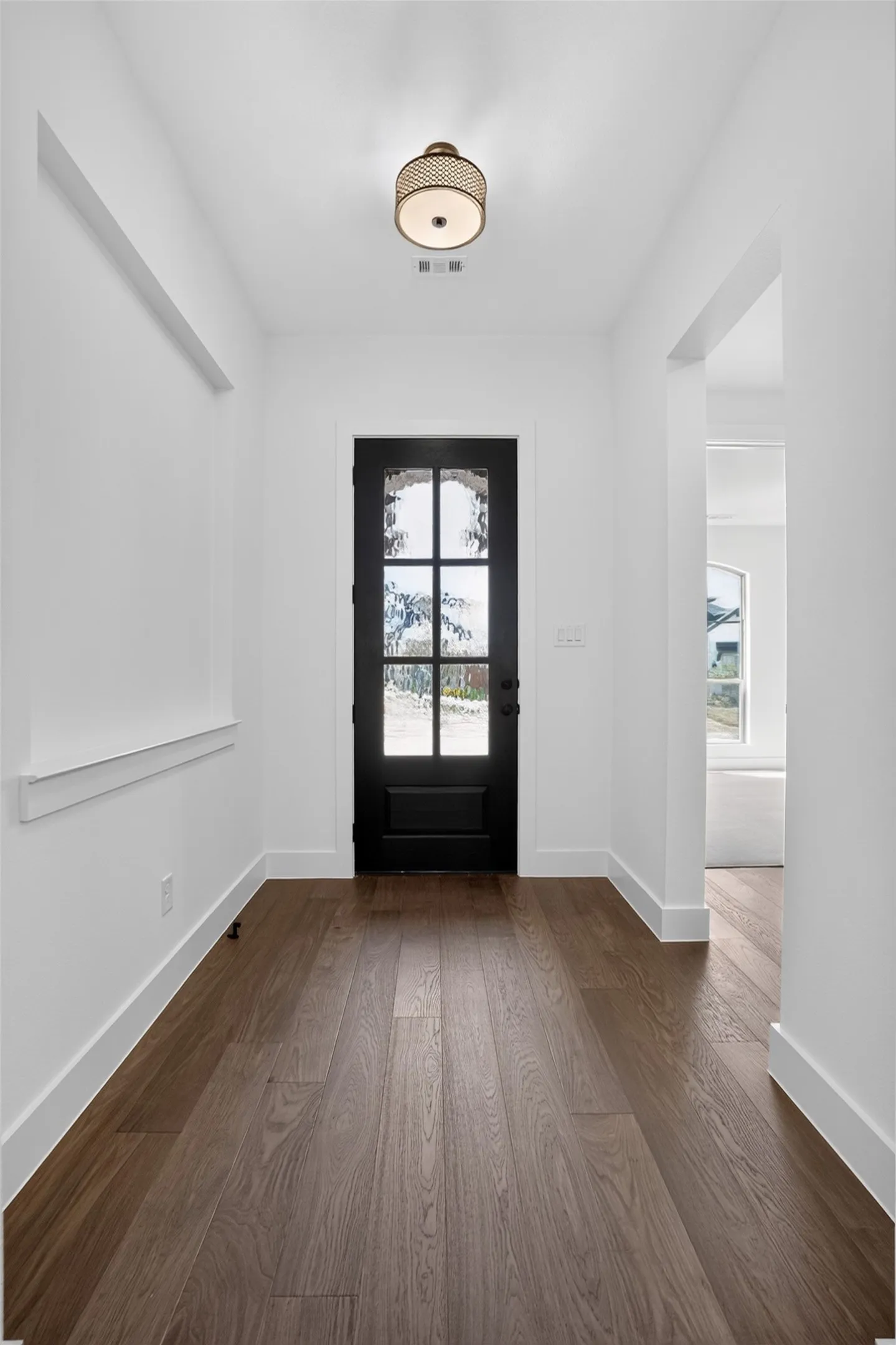 Entryway featuring wood-finish flooring, white walls, and a black front door with decorative glass