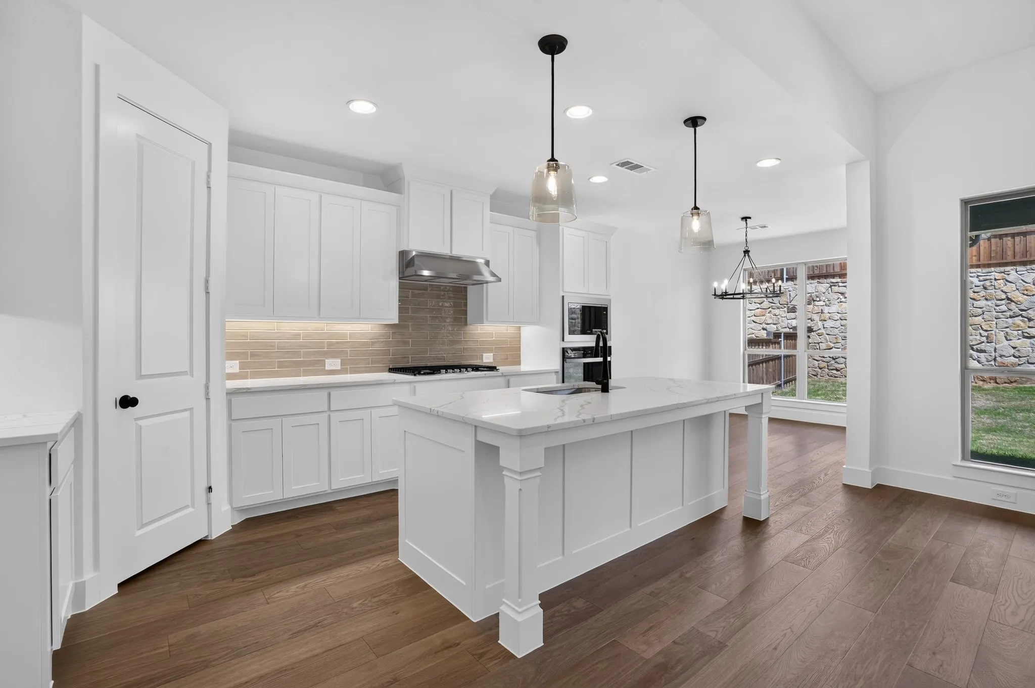 Kitchen featuring a center island with countertop, pendant lighting, white cabinetry, integrated oven, and wood-finish flooring