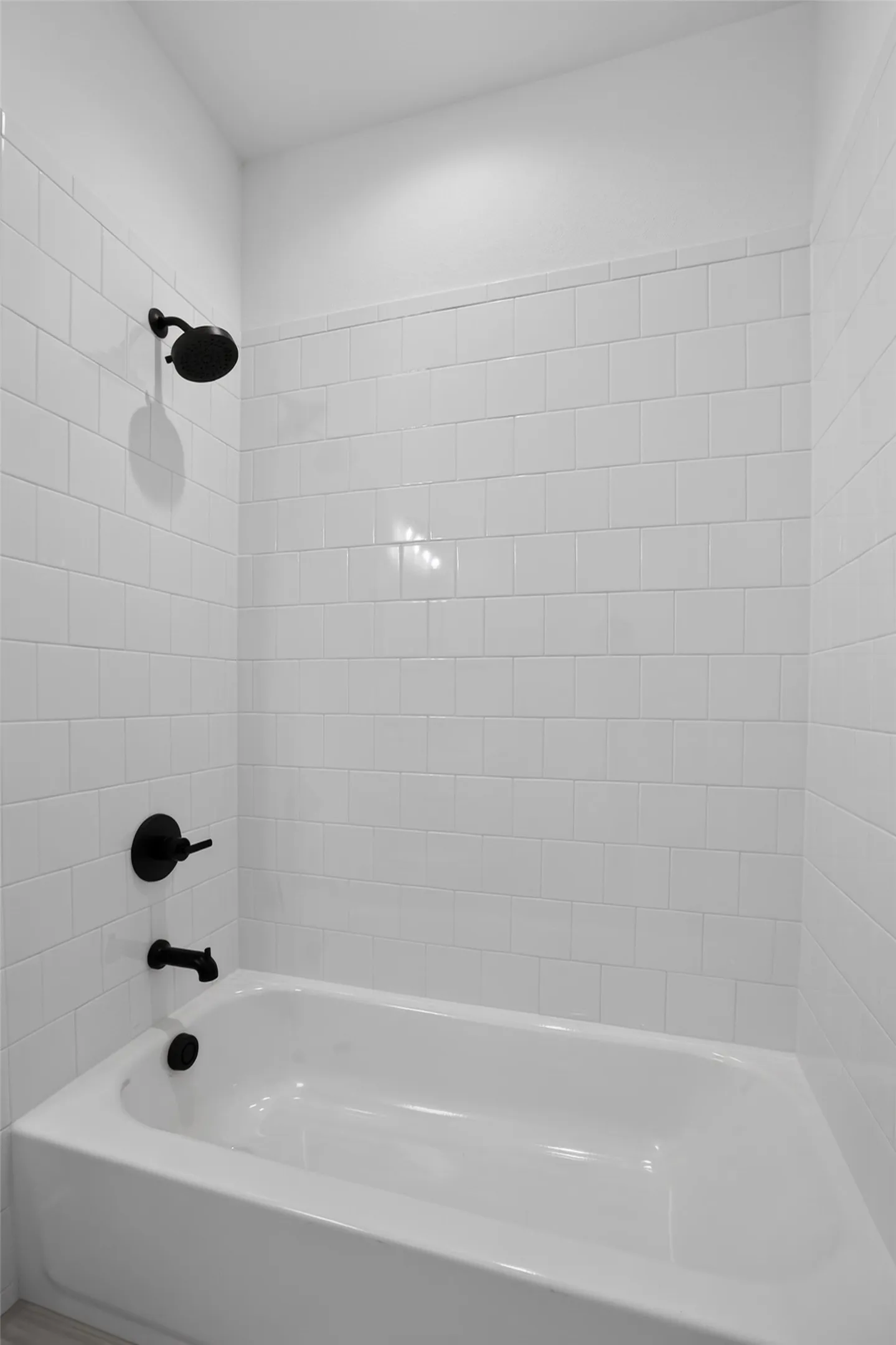 White subway tile surround with matte black fixtures and a white tub