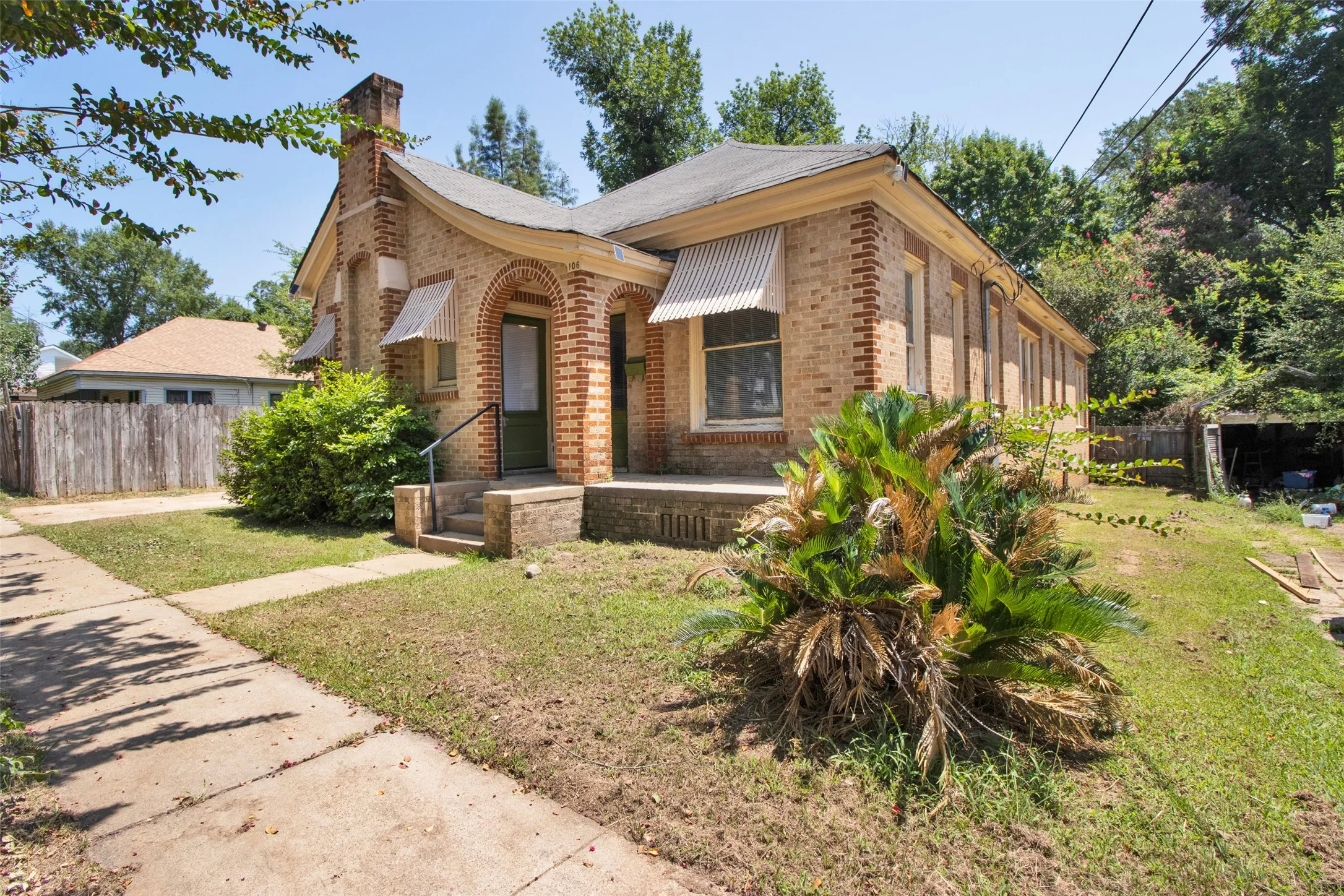Brick exterior with decorative corbeling, arched entryway, and striped window awnings