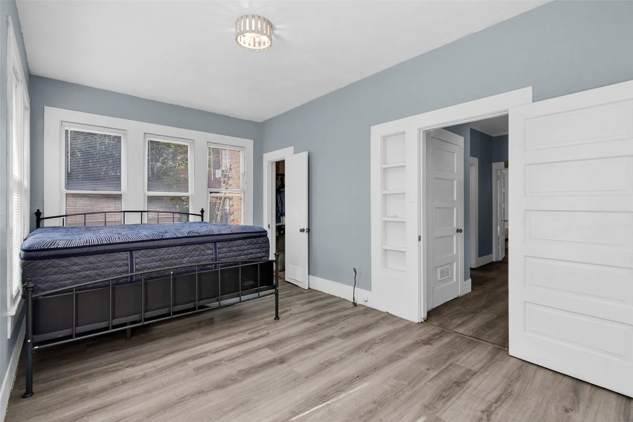 Room featuring wood-finish flooring, light blue wall paint, white trim, and a contemporary ceiling fixture