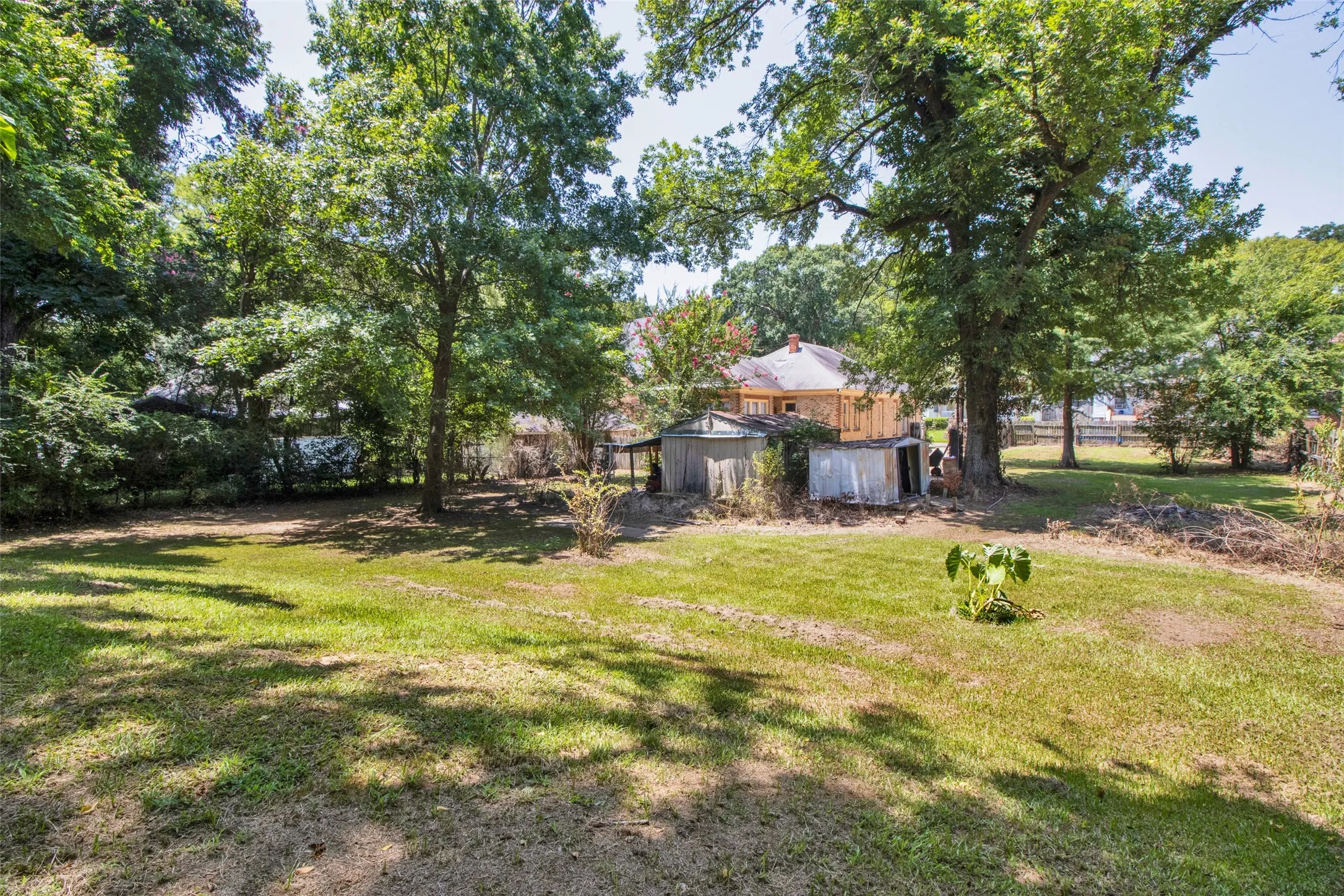 Spacious backyard featuring extensive green space and mature trees providing natural shade