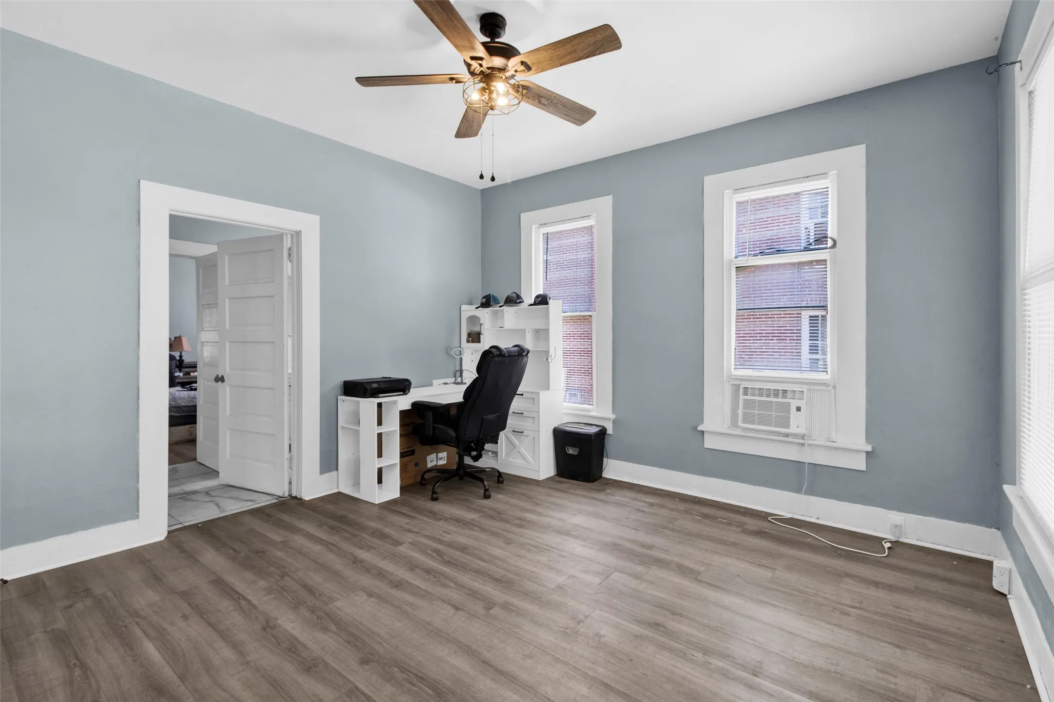 Room featuring wood-finish flooring, light blue walls, and white trim