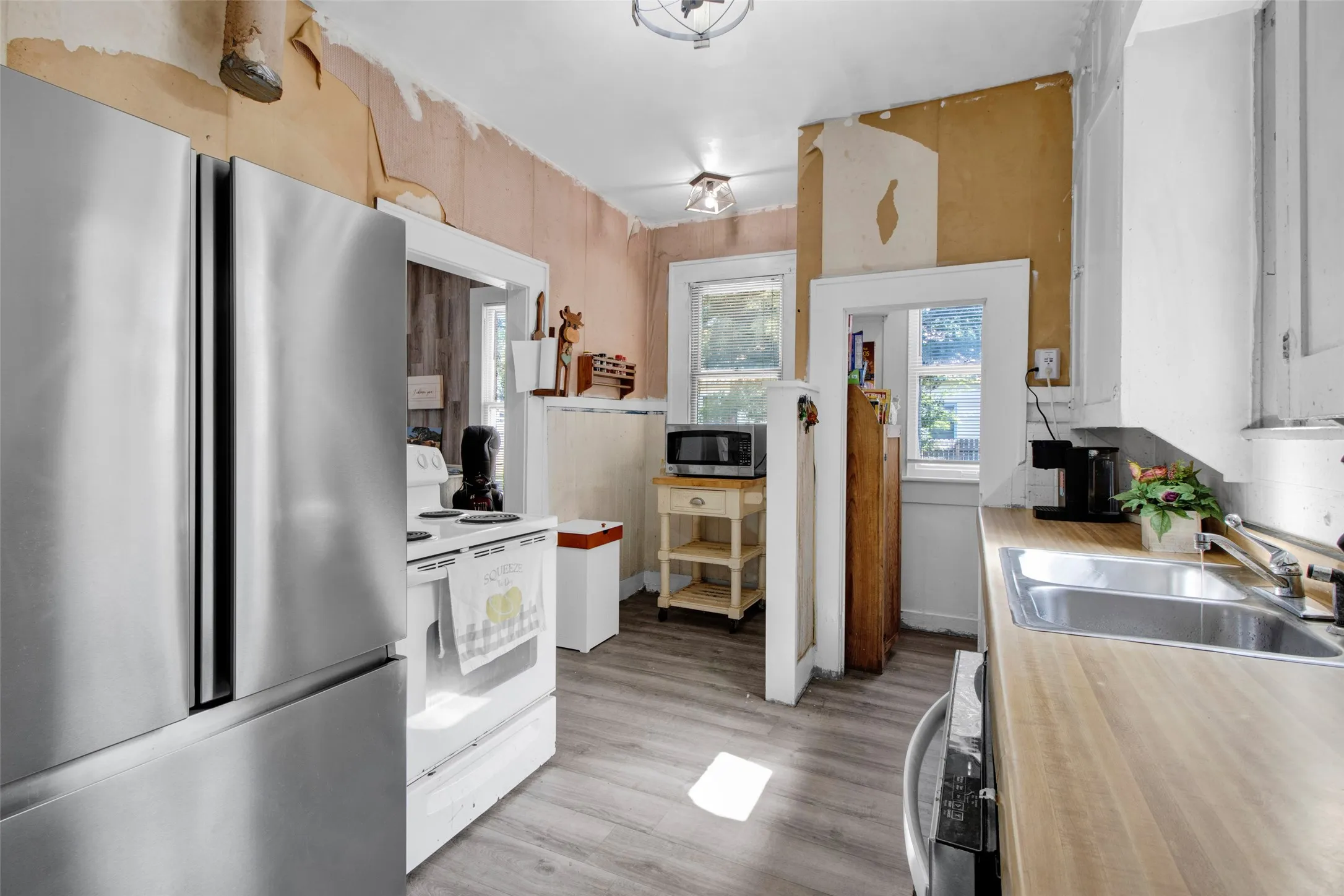 Kitchen featuring wood-finish flooring, butcher block countertops, stainless steel refrigerator, and a stainless steel sink with a chrome faucet
